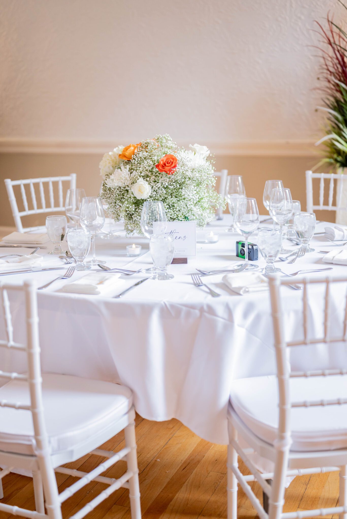 Bright wedding tablescape with orange-infused floral arrangements, including baby's breath and white florals. Classic Calgary Wedding with Bright Colours & Bathtub Portraits.