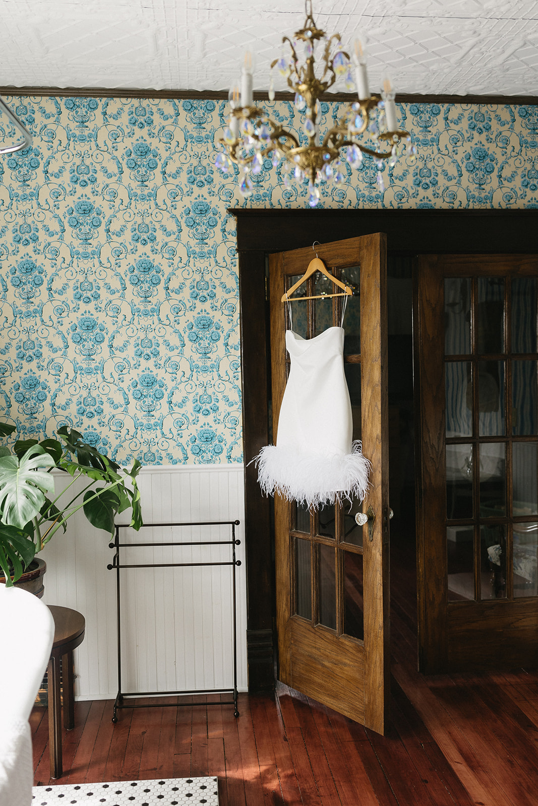 Chic short, feather-lined bridal gown hanging in vintage Hollywood glam home, styled and captured by Photography by Taiya.