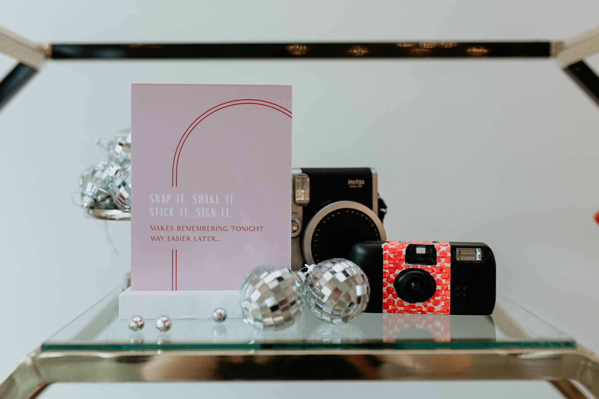 Chic wedding reception decor featuring a fusion of modern and retro aesthetics: modern decor elements alongside retro-inspired stationery and signage, styled with vintage cameras and mini disco balls, creating a dynamic visual contrast.