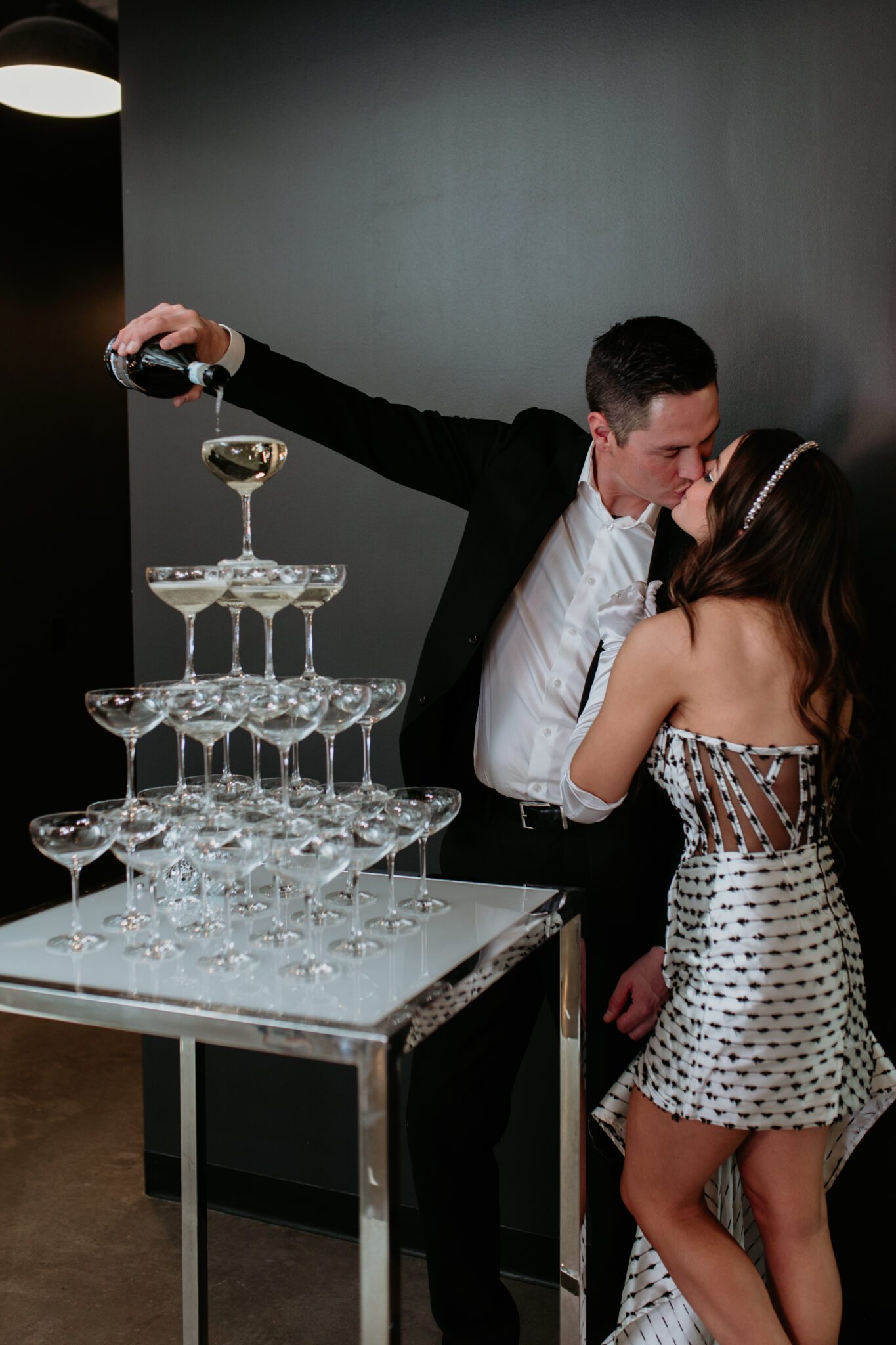 Bride and groom pouring champagne tower at retro-inspired wedding at The Brownstone in Calgary, Alberta. Bride wearing show-stopping black and white gown. 