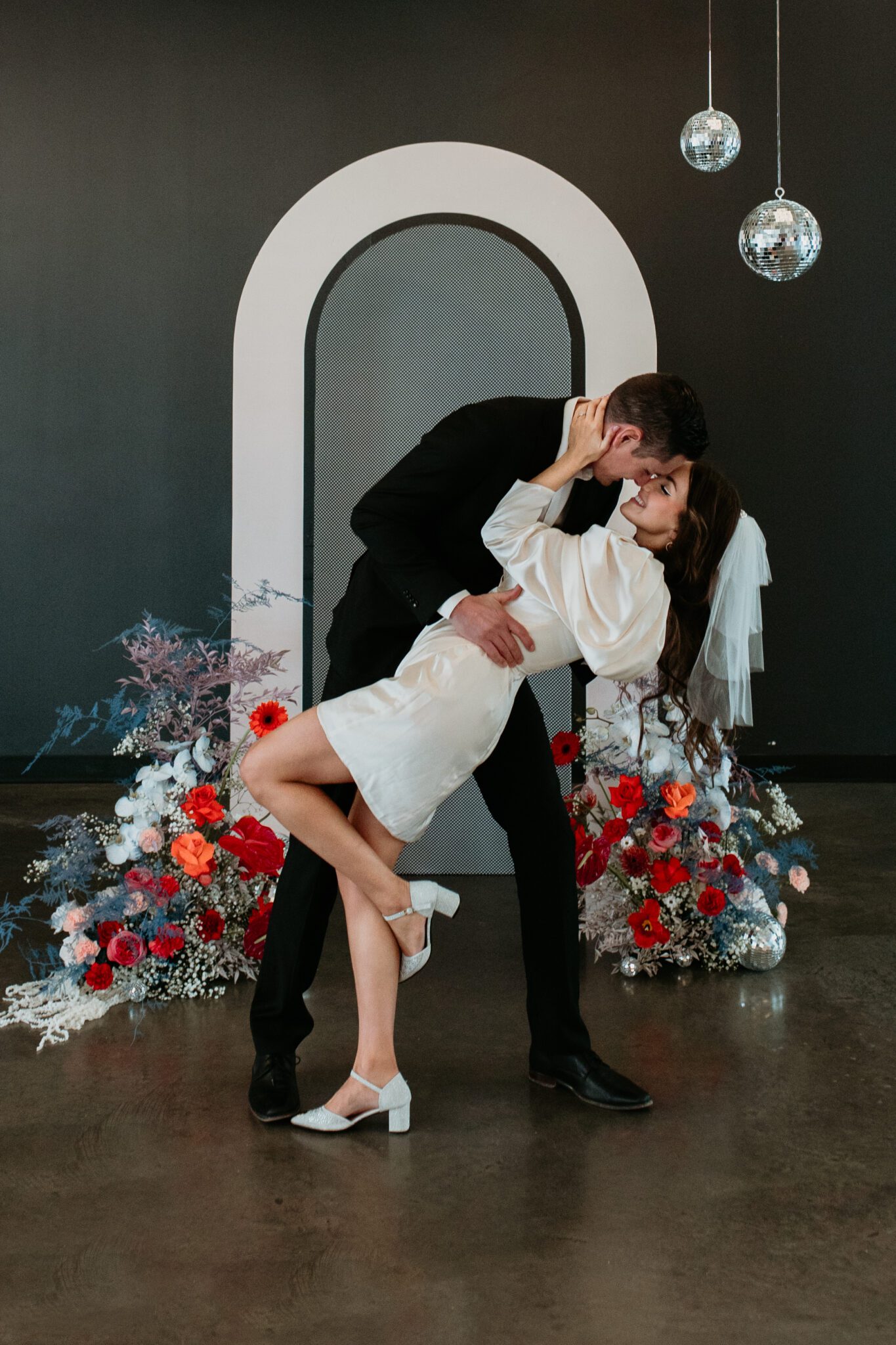 Couple kisses during bold retro-inspired wedding, combining vibrant colours, sleek lines, and nostalgic elements for a unique celebration.