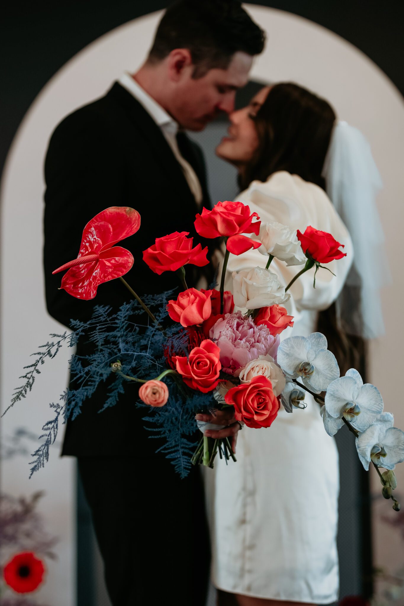 Couple kisses during bold retro-inspired wedding, combining vibrant colors, sleek lines, and nostalgic elements for a unique celebration.