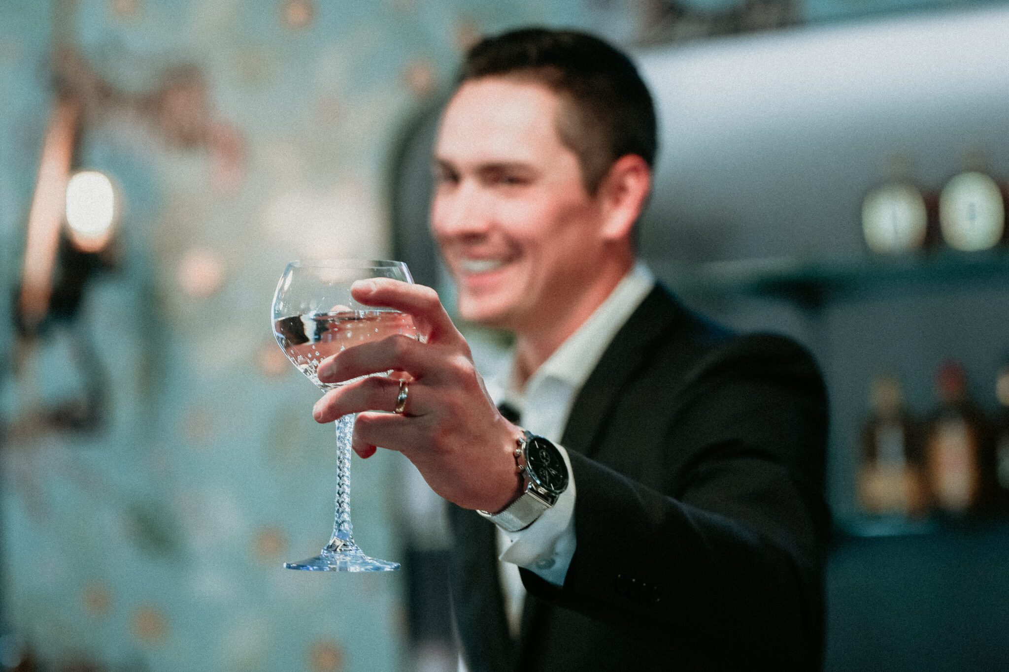 Stylish groom holding our cocktail during bold modern wedding with retro styles with eye-catching accents.