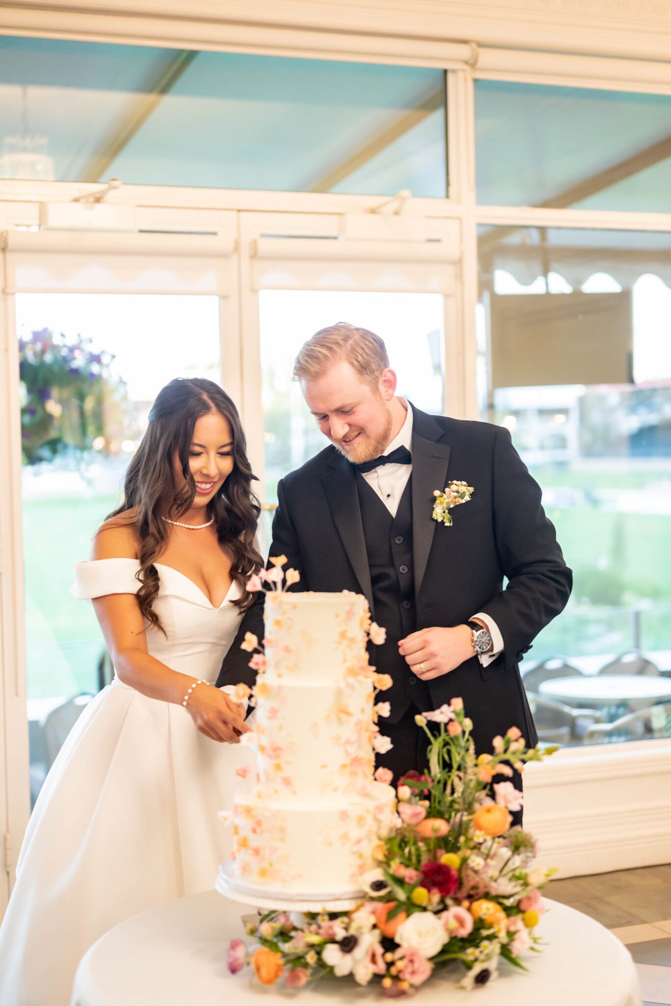 Couple cuts their two-tiered, floral-inspired wedding cake at their wedding reception at Spruce Meadows.