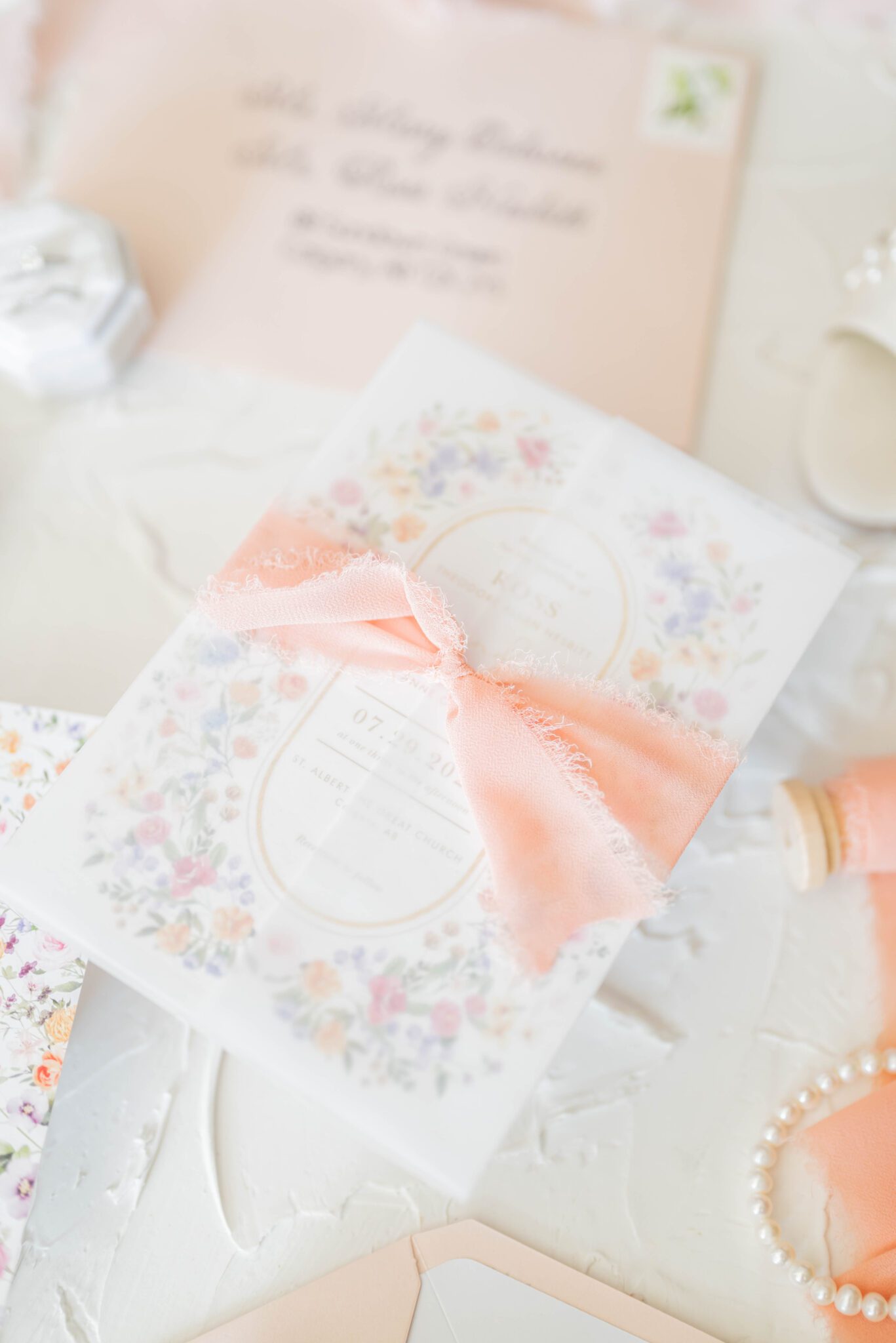 Floral-printed custom wedding stationery, flatlay photos inspiration, with light peach ribbon and accent colour.