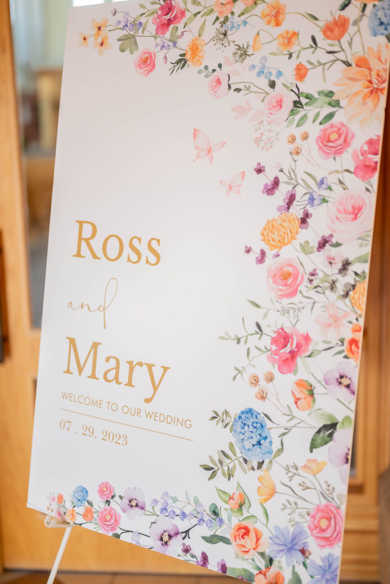 Floral-patterned custom welcome wedding sign at the front of the ceremony church location, whimsical garden wedding.