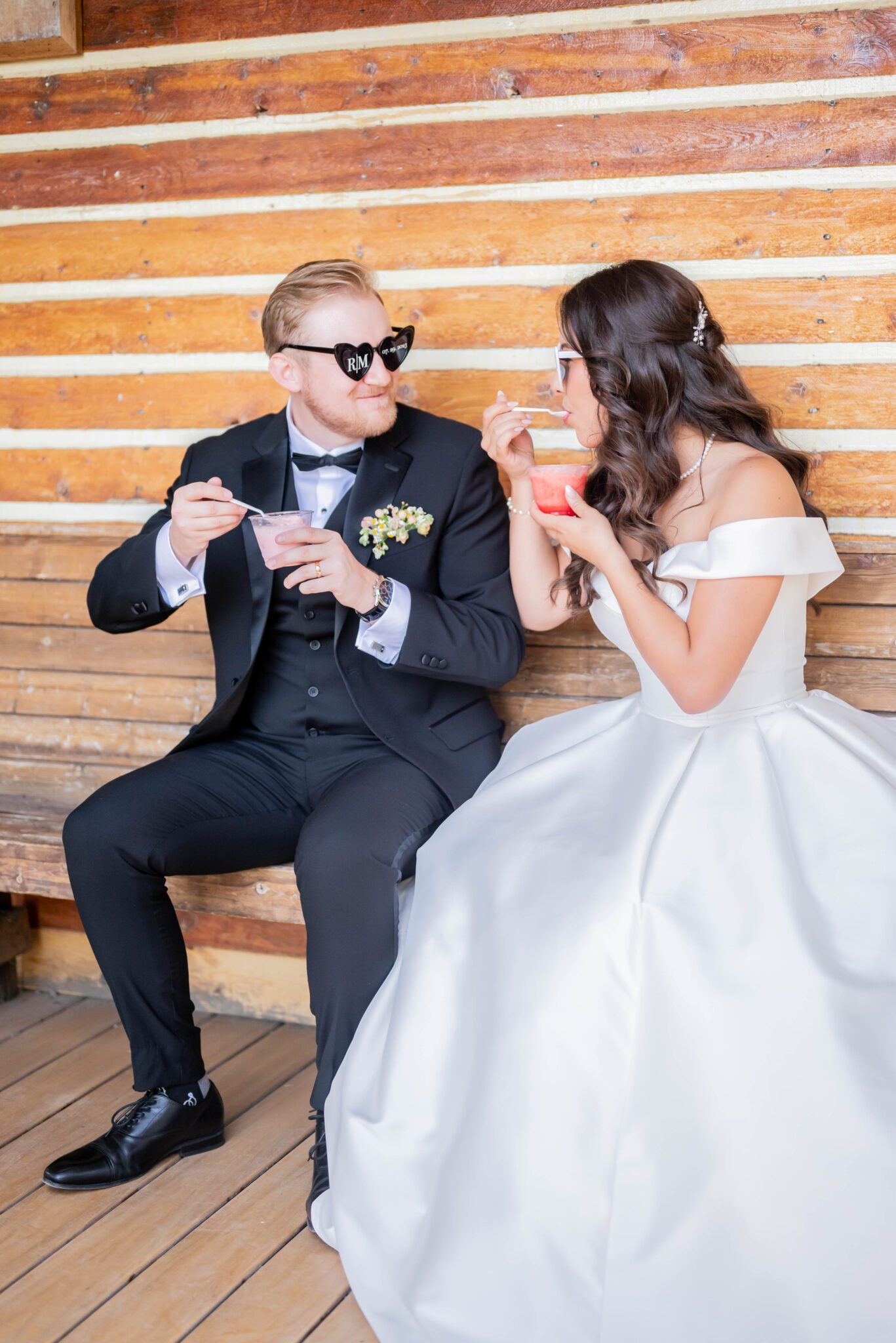 Bride and groom share icecream together at their whimsical garden wedding, featuring their heart-shaped custom sunglasses.