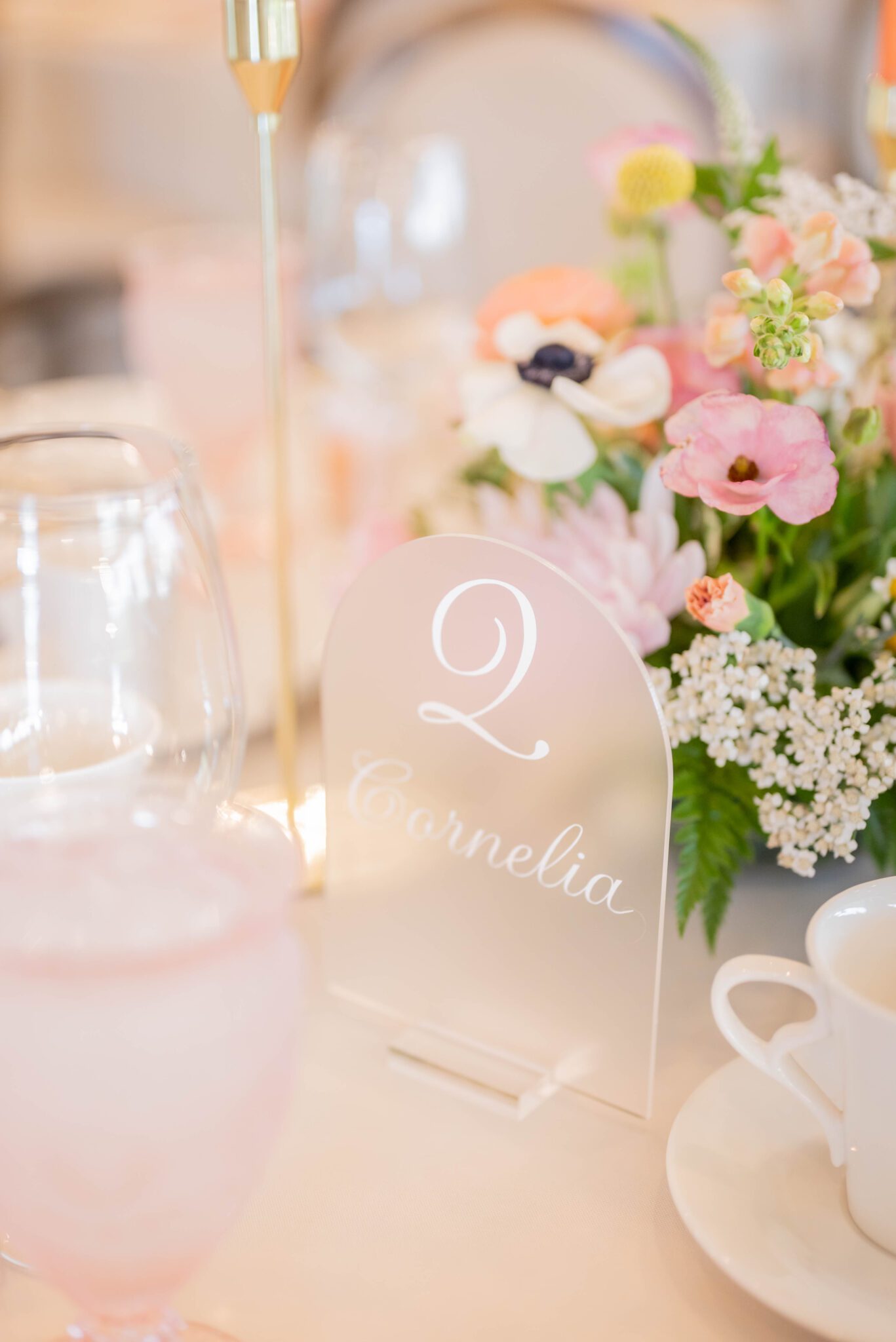 Handwritten, custom wedding table numbers, featuring flower names from Taylor Swift songs, surrounded by colourful floral arrangements. 