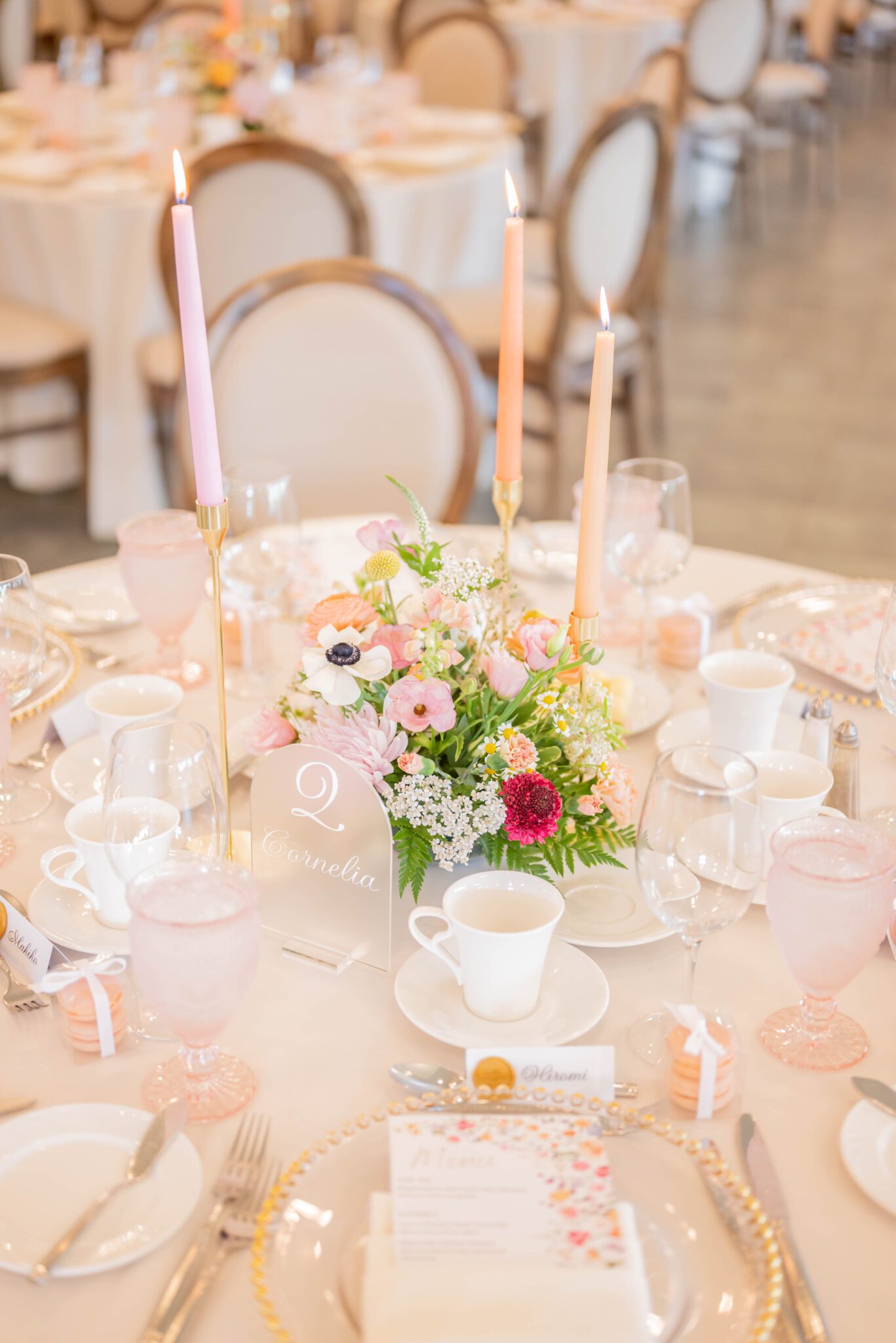 Detailed photo of garden party tablescape design, featuring pastel taper candles, wildflower bouquet arrangements, and dainty glassware. 