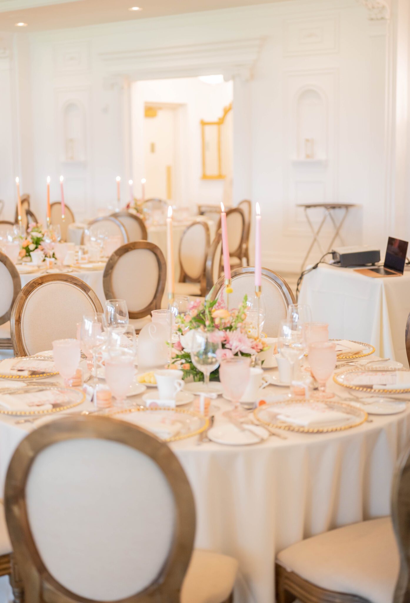 Photo of the whimsical wedding reception details at Spruce Meadows, featuring pastel taper candles, dainty glassware, and floral-printed stationery. 