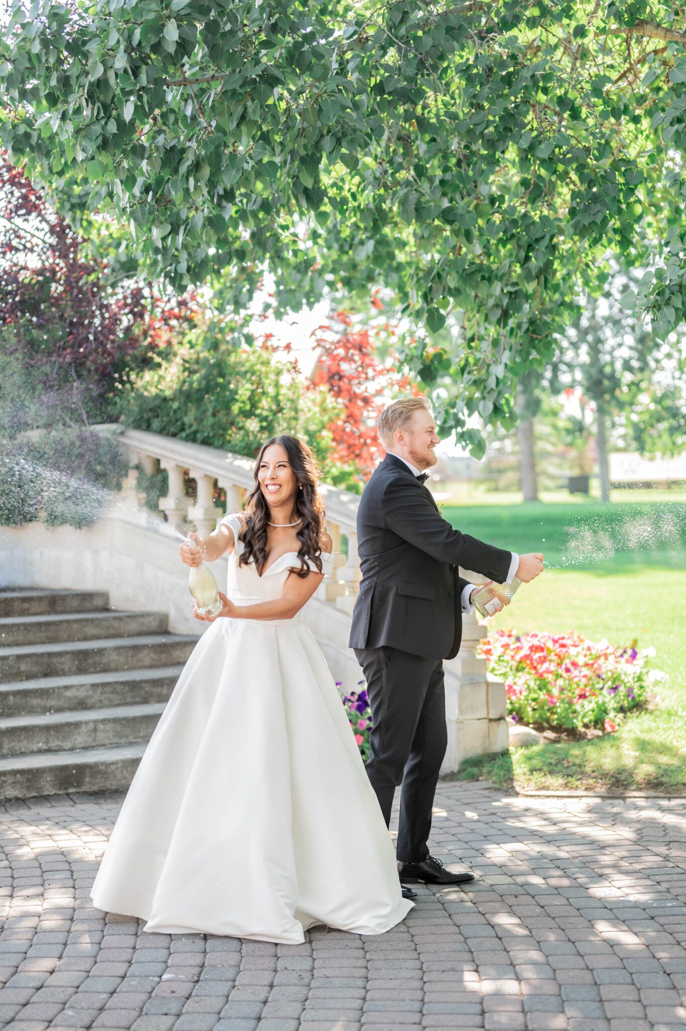 Bride and groom pop a bottle of champagne in celebration at their whimsical garden wedding in Spruce Meadows.