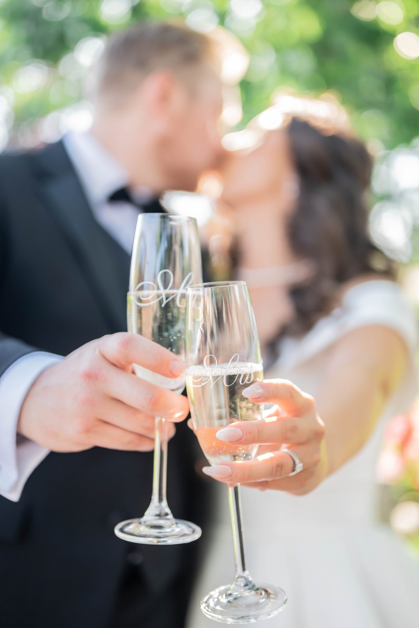 Couple cheers His & Her glasses of champagne while sharing a kiss. 