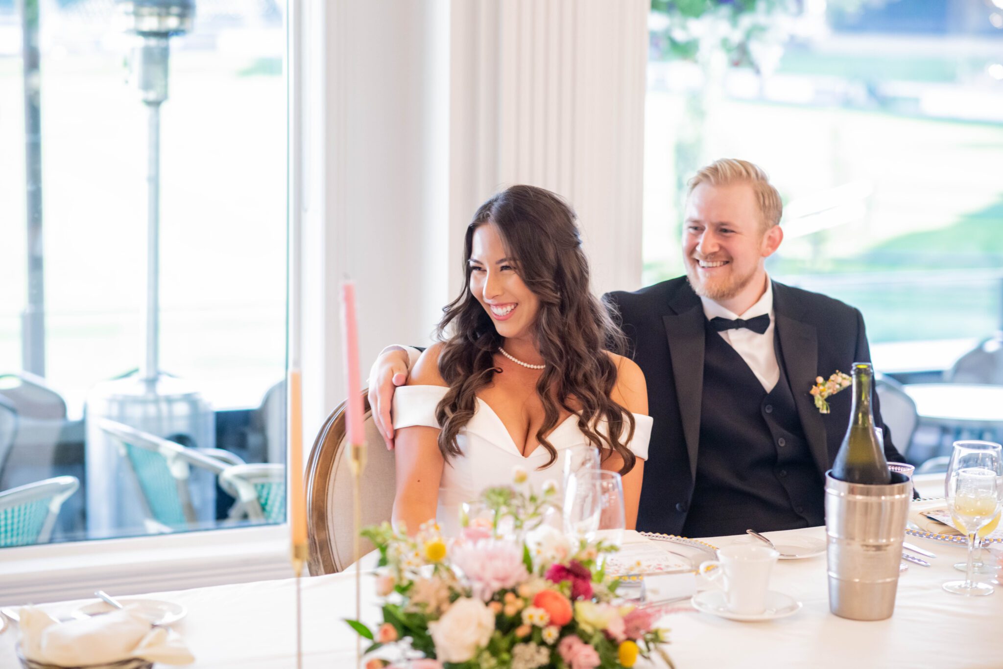 Couple smiling during wedding speeches at their whimsical garden wedding at Spruce Meadows. 