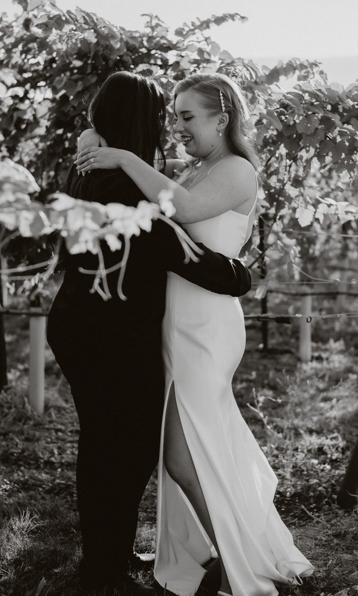 Black and white portrait of couple embracing in an Okanagan vineyard, at their vineyard wedding reception with breathtaking views.