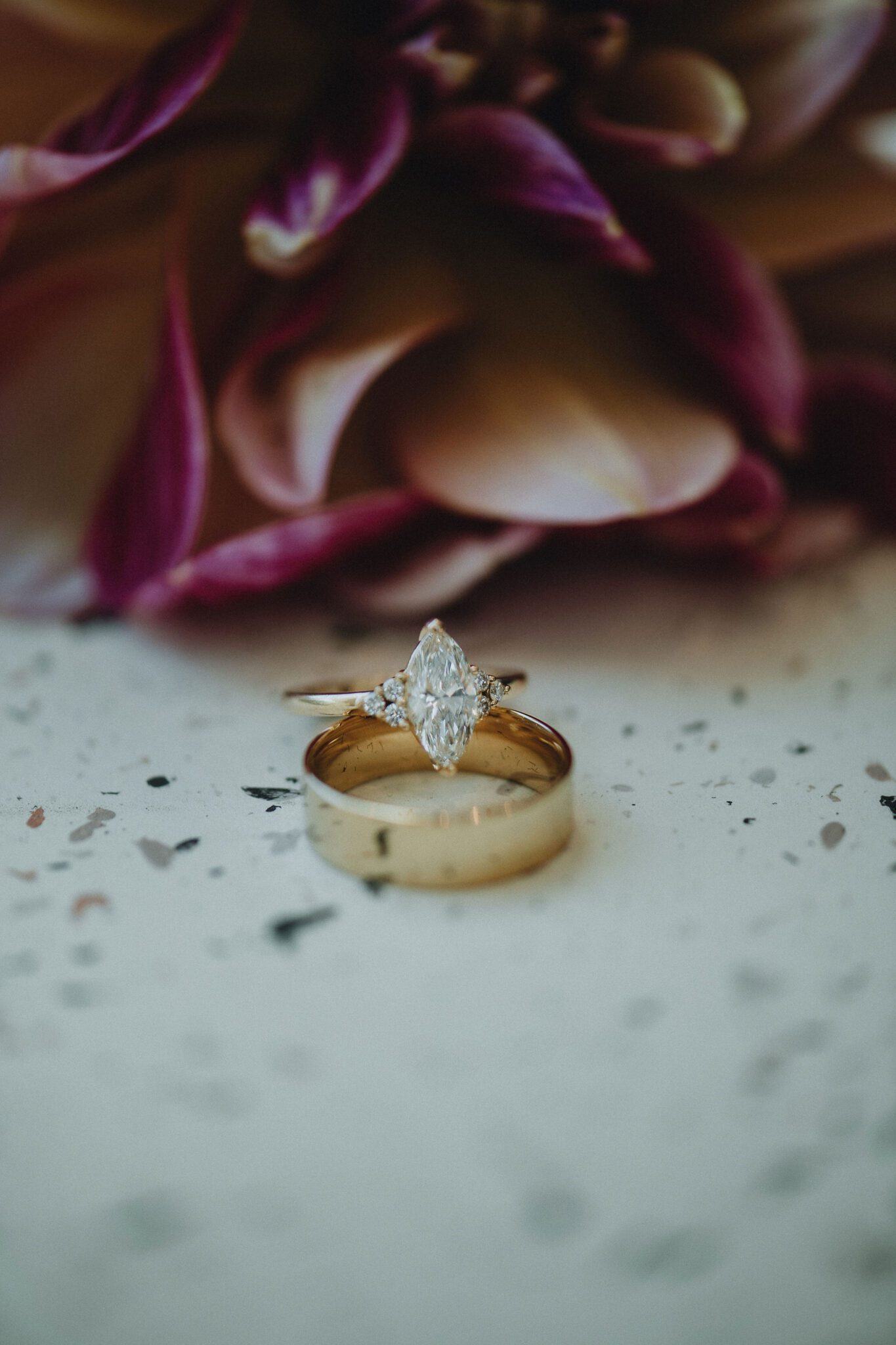 Close up portrait of the bride's ring set, with purple-coloured florals in the background. 