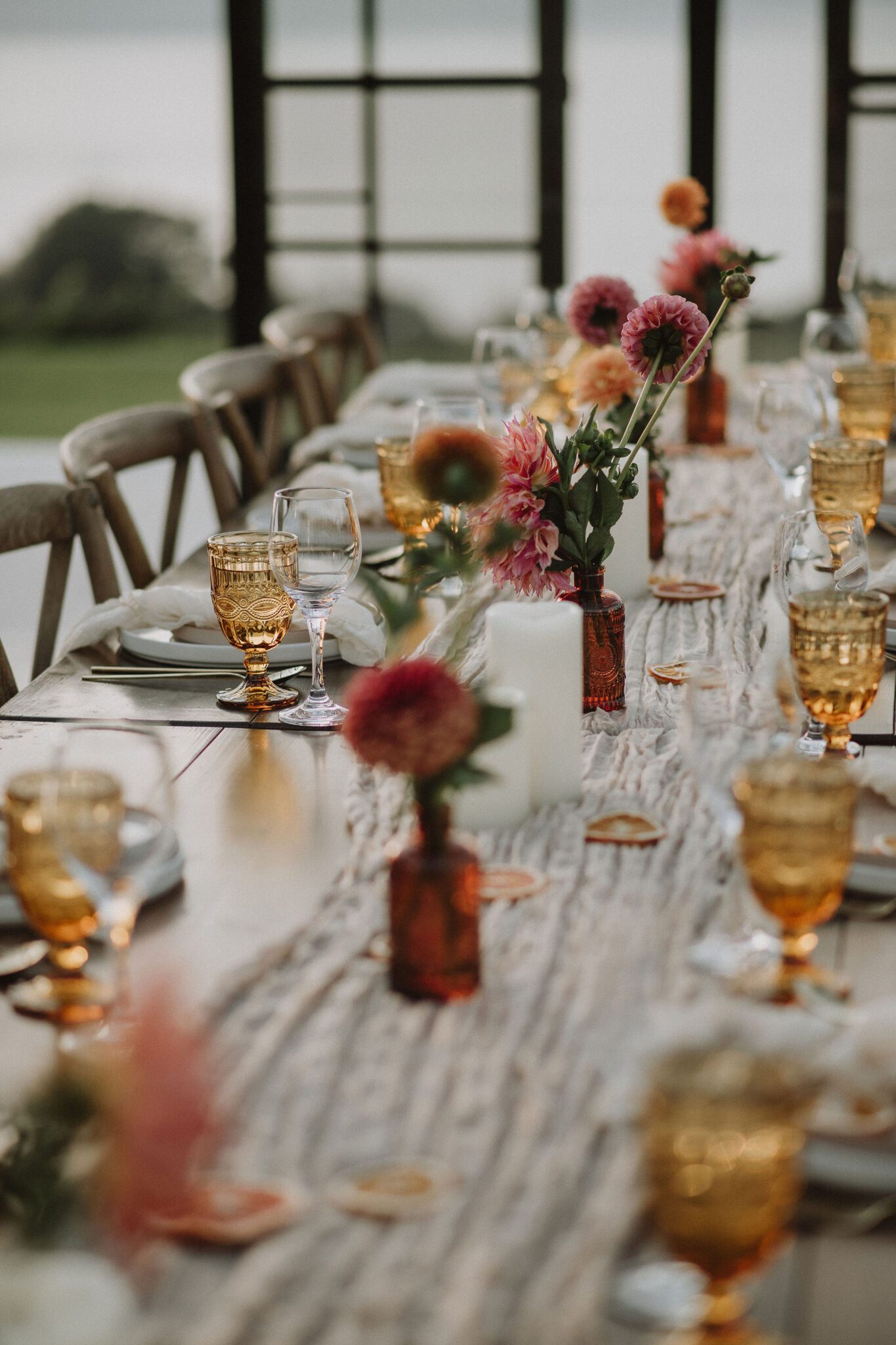 Close up detailed photo of reception tablescape at intimate vineyard wedding, featuring colourful bud vases and vintage glassware. 