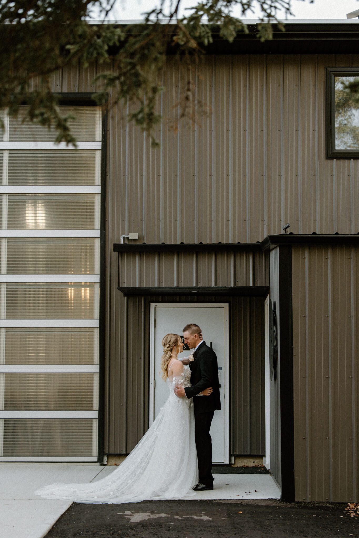 Far away portrait of bride and groom standing in front of 52 North Wedding Venue, warm and moody wedding inspiration. 