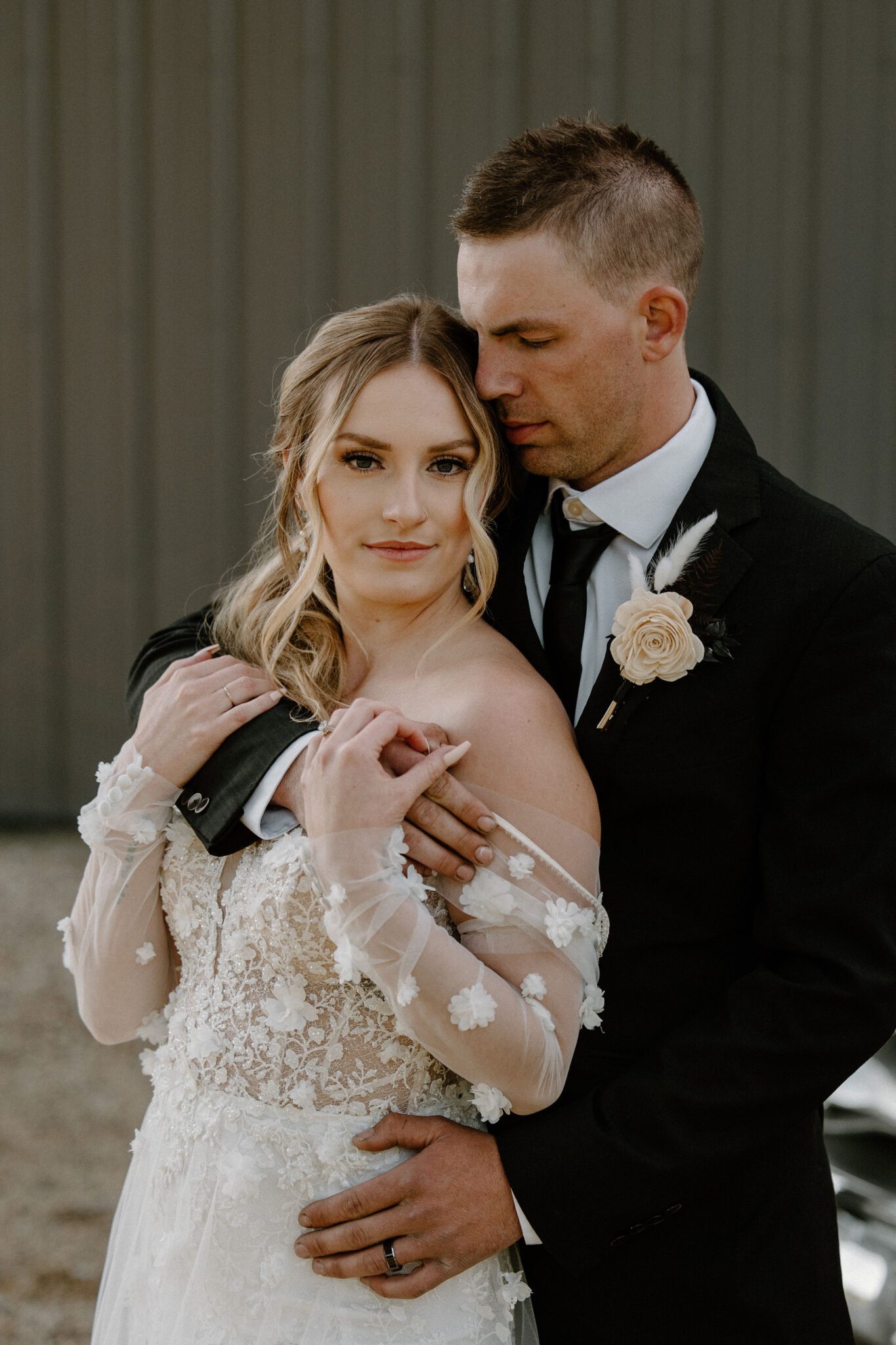 Portrait of bride and groom embracing at 52 North Venue, bride in floral-detailed tulle gown and elegant ponytail updo, warm and moody wedding inspiration. 