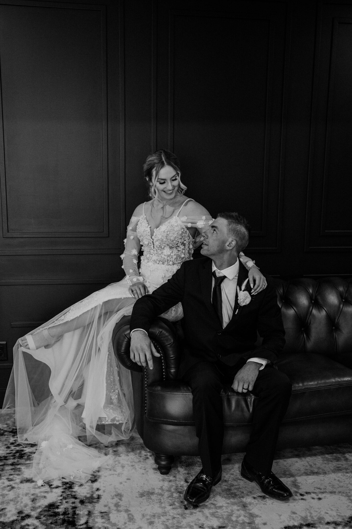 Black and white portrait of bride and groom sitting on vintage couch in 52 North Venue.