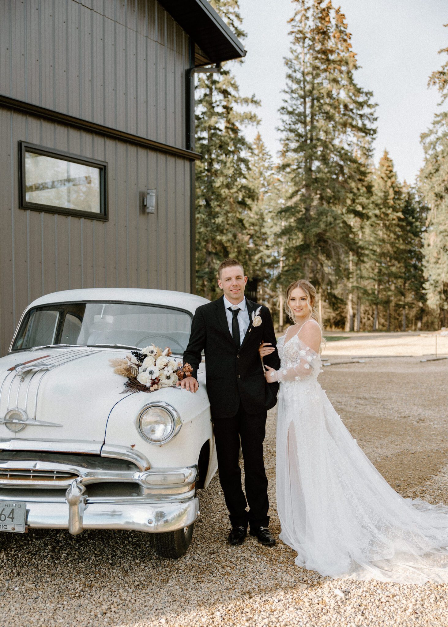 Formal wedding portrait of bride and groom at 52 North Venue standing beside their vintage getaway car, featuring the elegant bridal bouquet with rich textures and tones. 