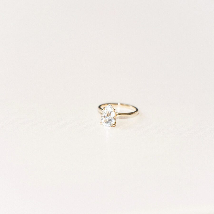 Another example of an engagement ring trend, featuring a pear-shaped engagement ring with a simple gold band. 