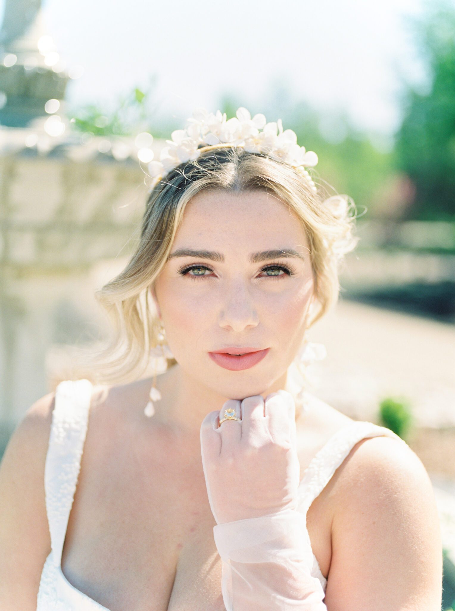 A beautiful bride wearing floral and pearl headpiece by Joanna Bisley Designs, featuring classic spring bridal makeup inspiration by Veil Beauty Co. Summer bridal fashion inspiration, sheer tulle bridal gloves and sophistication lace gown. 
