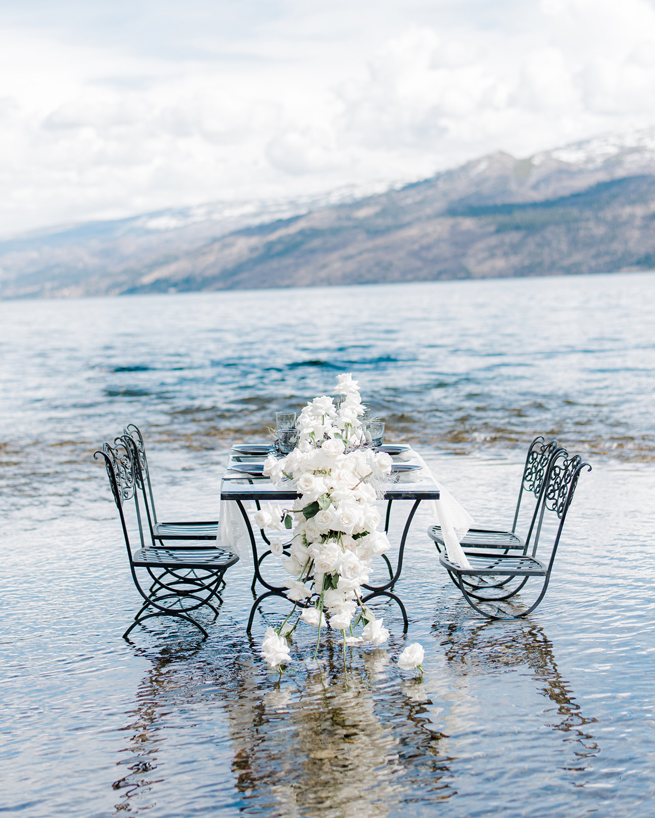 Intimate table setting outdoors in Peachland, BC, coastal chic wedding inspiration with the majestic backdrop of the Canadian Rockies. Tablescape adorned with stunning florals by JAM Florals.