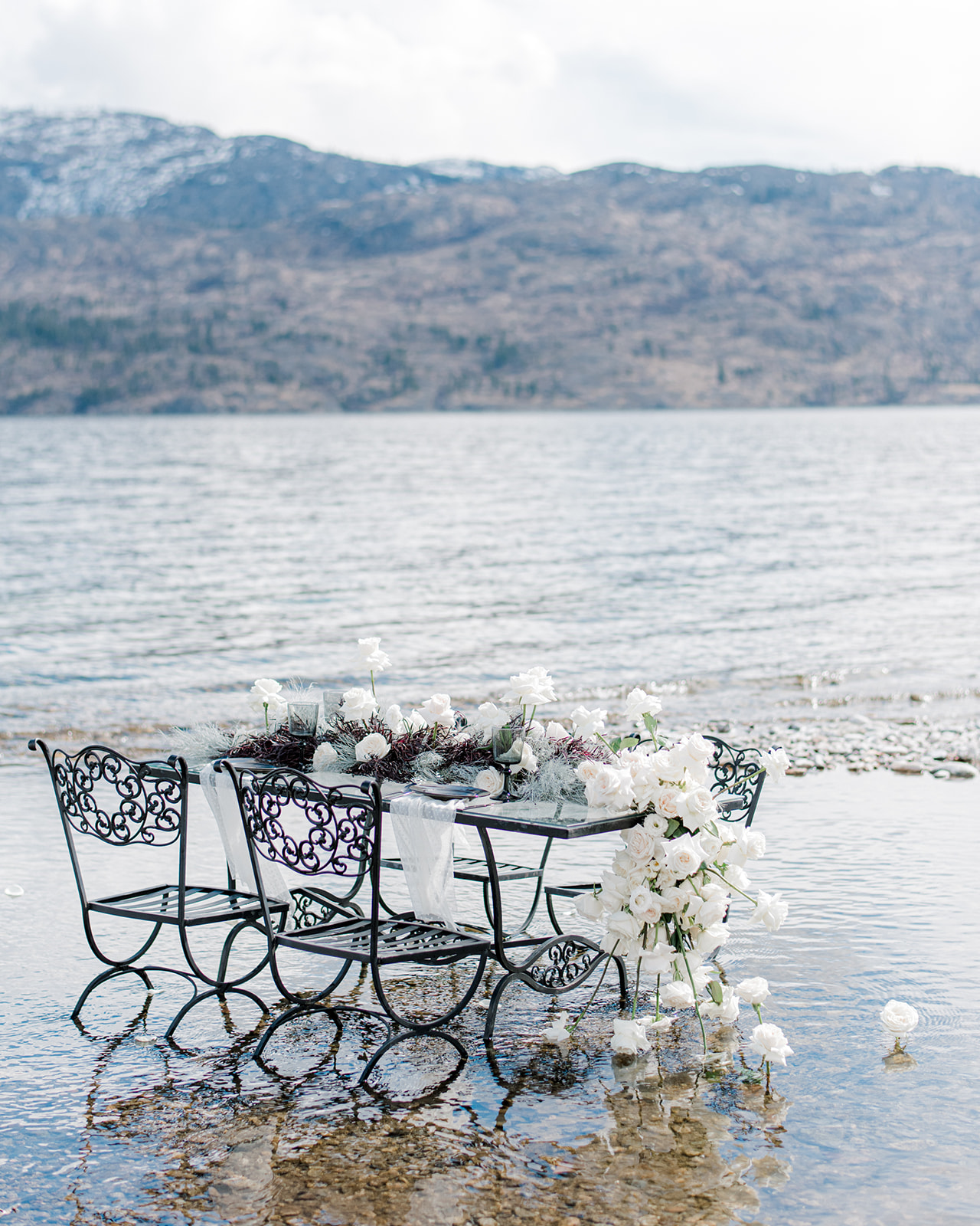 Intimate table setting outdoors in Peachland, BC, coastal chic wedding inspiration with the majestic backdrop of the Canadian Rockies. Tablescape adorned with stunning florals by JAM Florals.