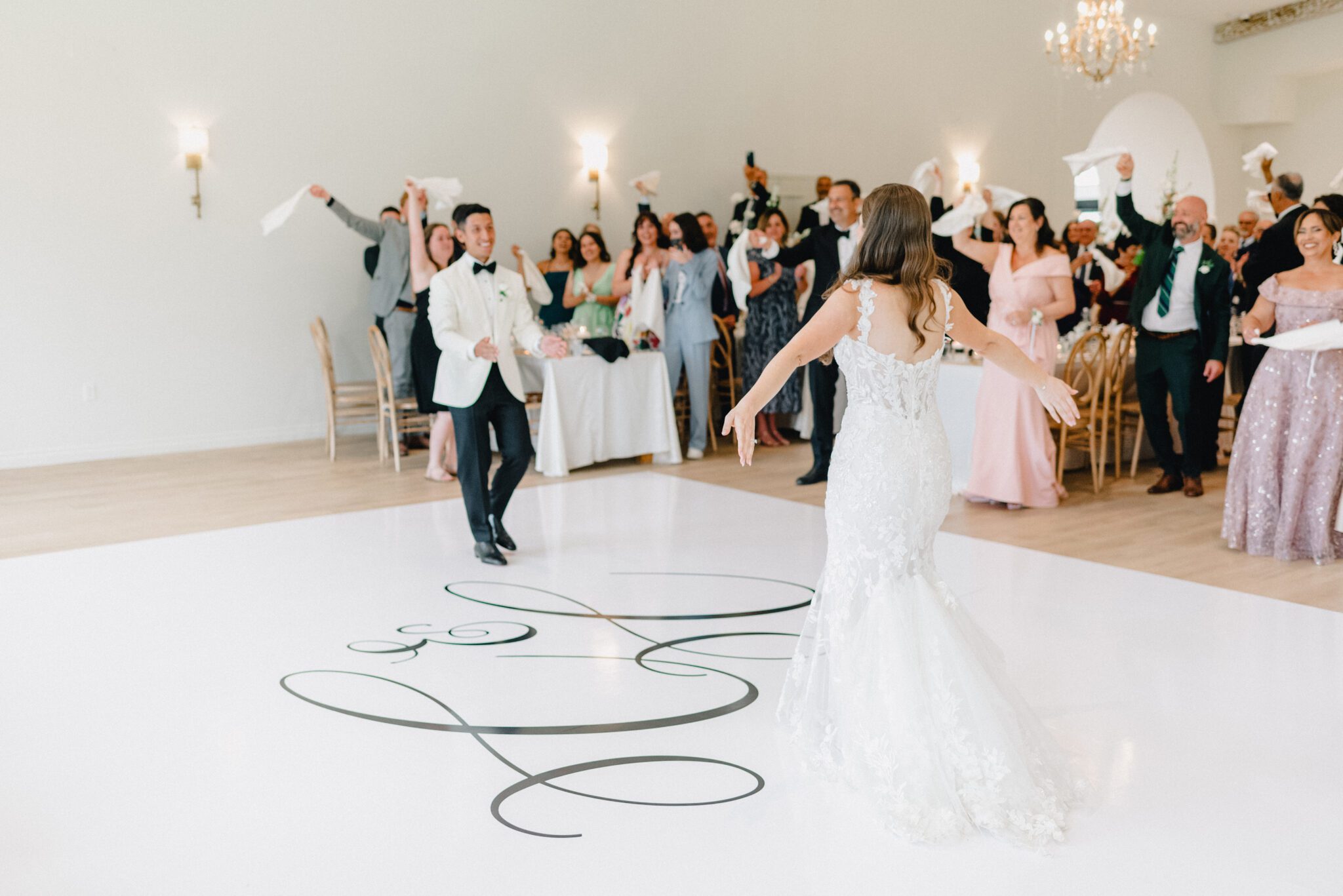 Bride and groom's first dance at wedding reception at Sparrow Lane Events in Alberta. Summer wedding features white roses, greenery blush decor accents and warm wood tones.