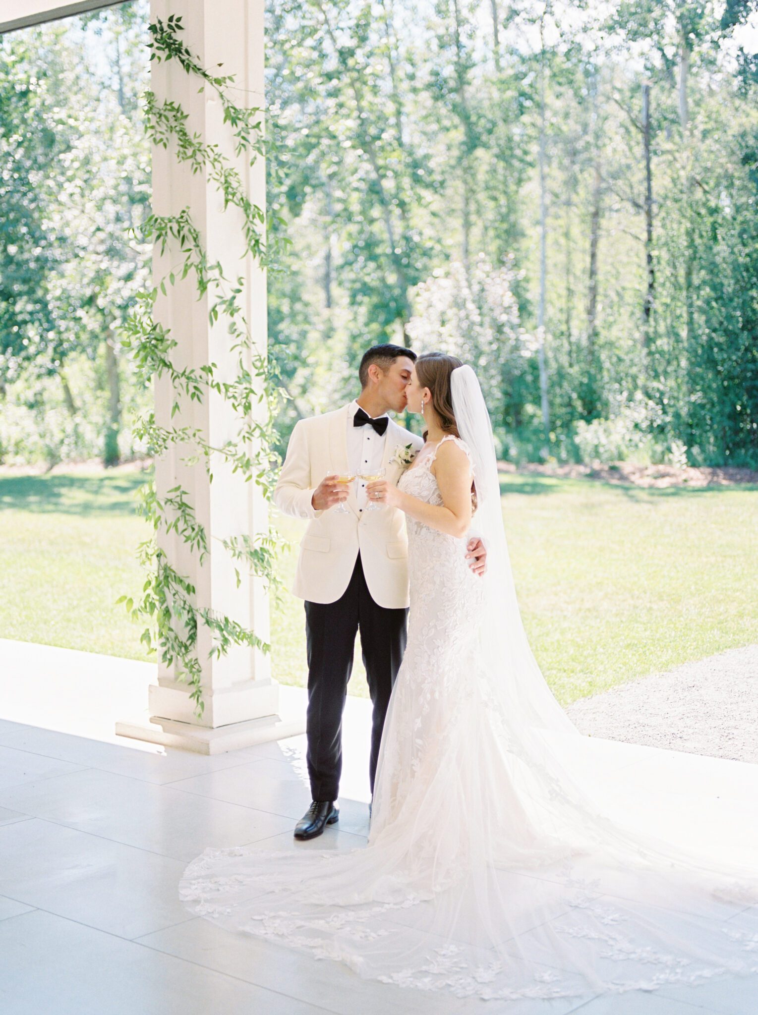 Elegant bride and groom embracing on patio at Sparrow Lane Events in Alberta. Classic colour palette of white, blush, and green wedding inspiration.