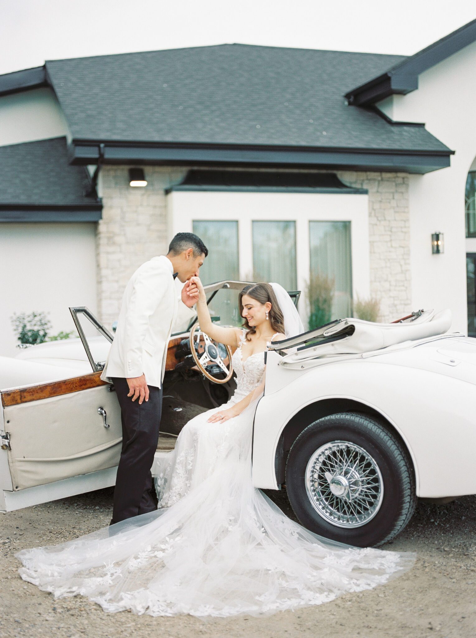 Elegant bride and groom with a vintage car outside of Sparrow Lane Events in Alberta. Classic colour palette of white, blush, and green wedding inspiration.