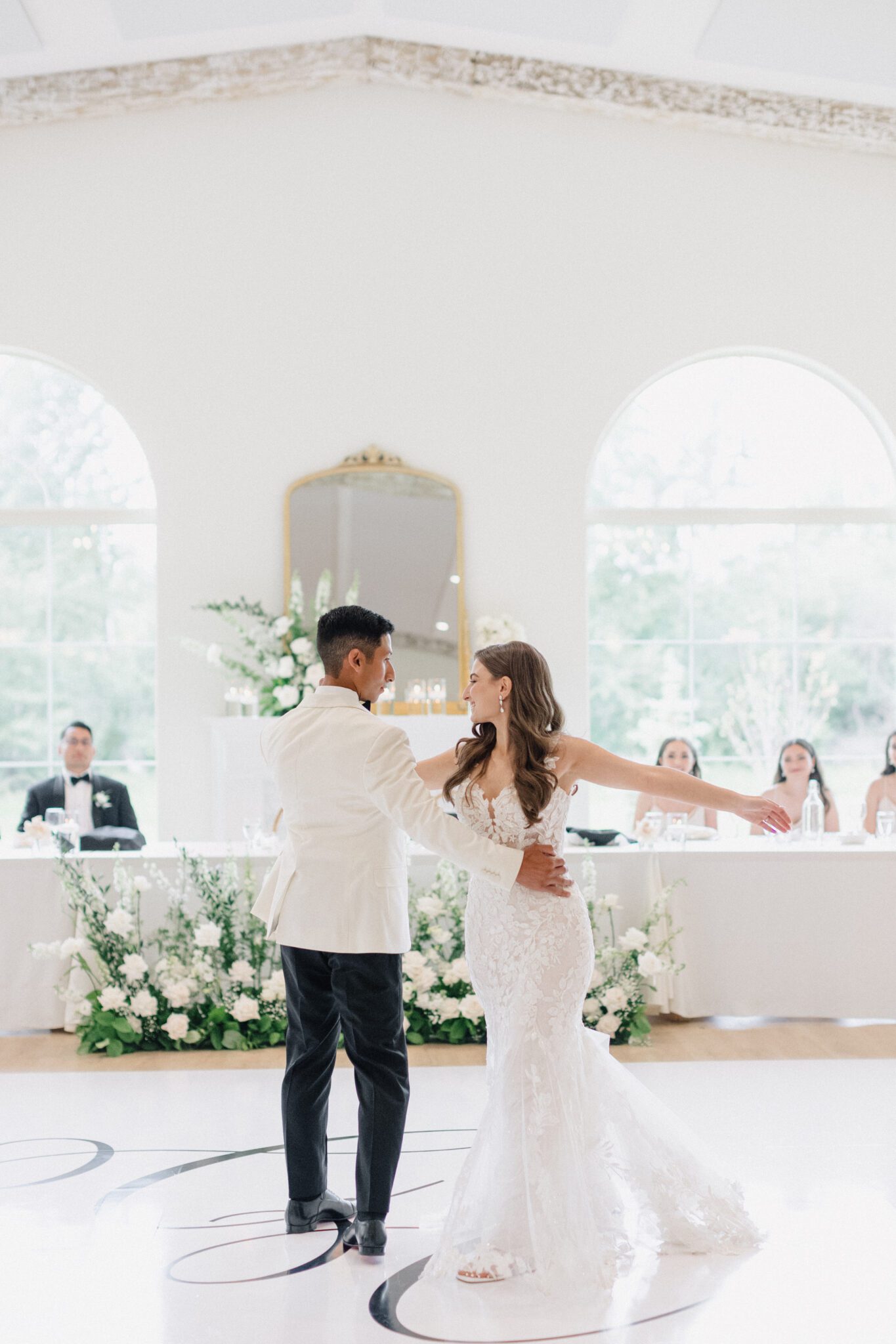 Bride and groom's first dance at wedding reception at Sparrow Lane Events in Alberta. Summer wedding features white roses, greenery blush decor accents and warm wood tones.