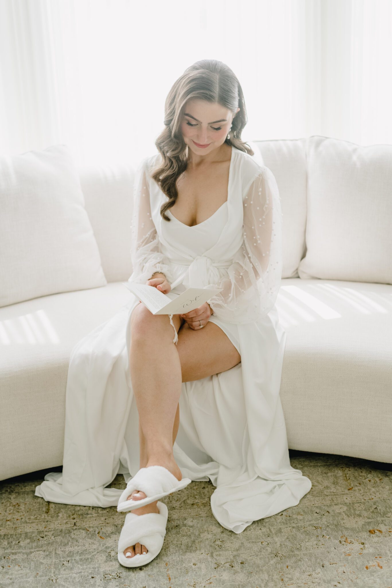 Stunning bride getting ready for her wedding day, wearing pearl encrusted bridal robe. 