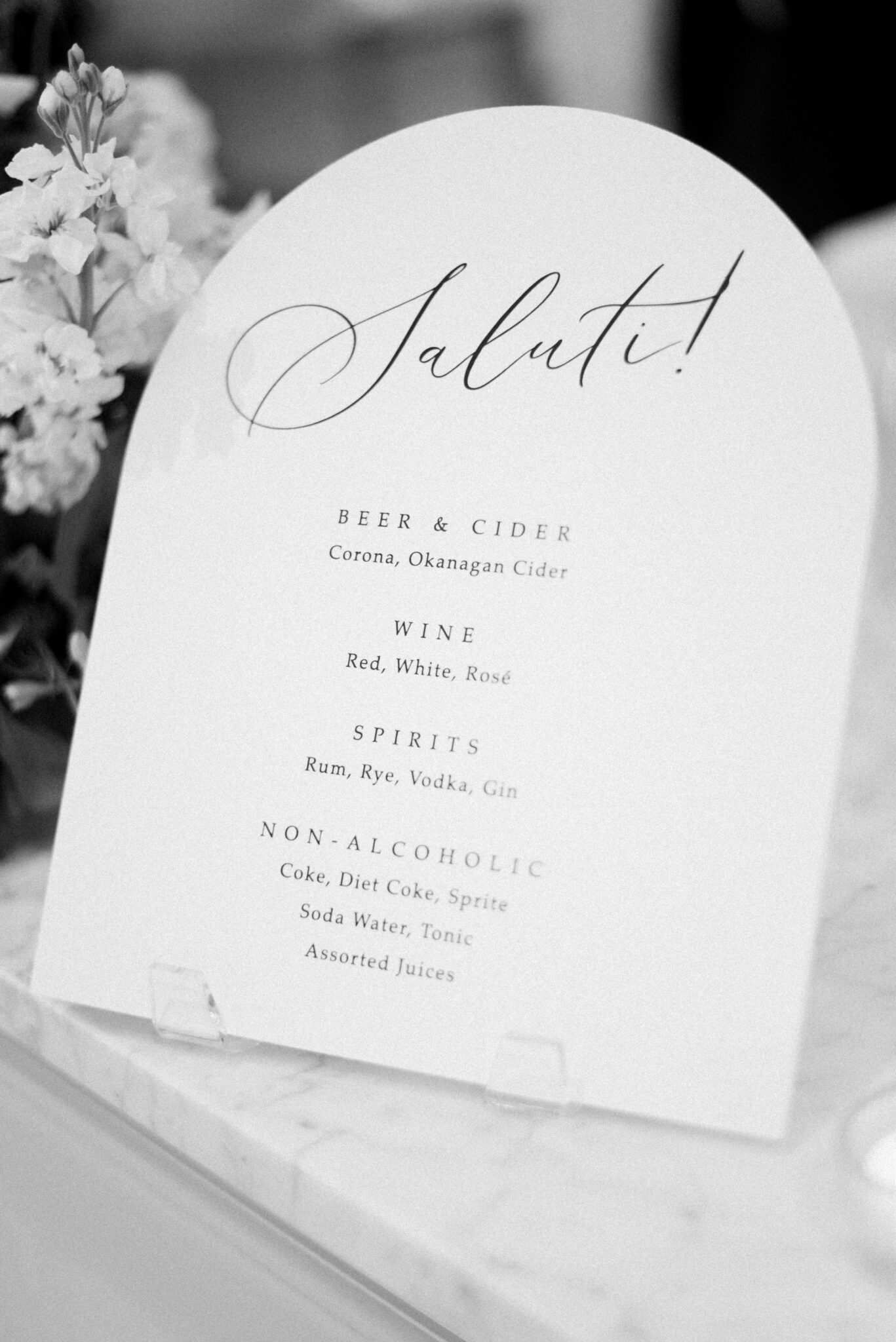 White and black wedding reception signage inspiration at an elegant summer wedding reception at Sparrow Lane Events in Alberta. Summer wedding features white roses, greenery blush decor accents and warm wood tones.