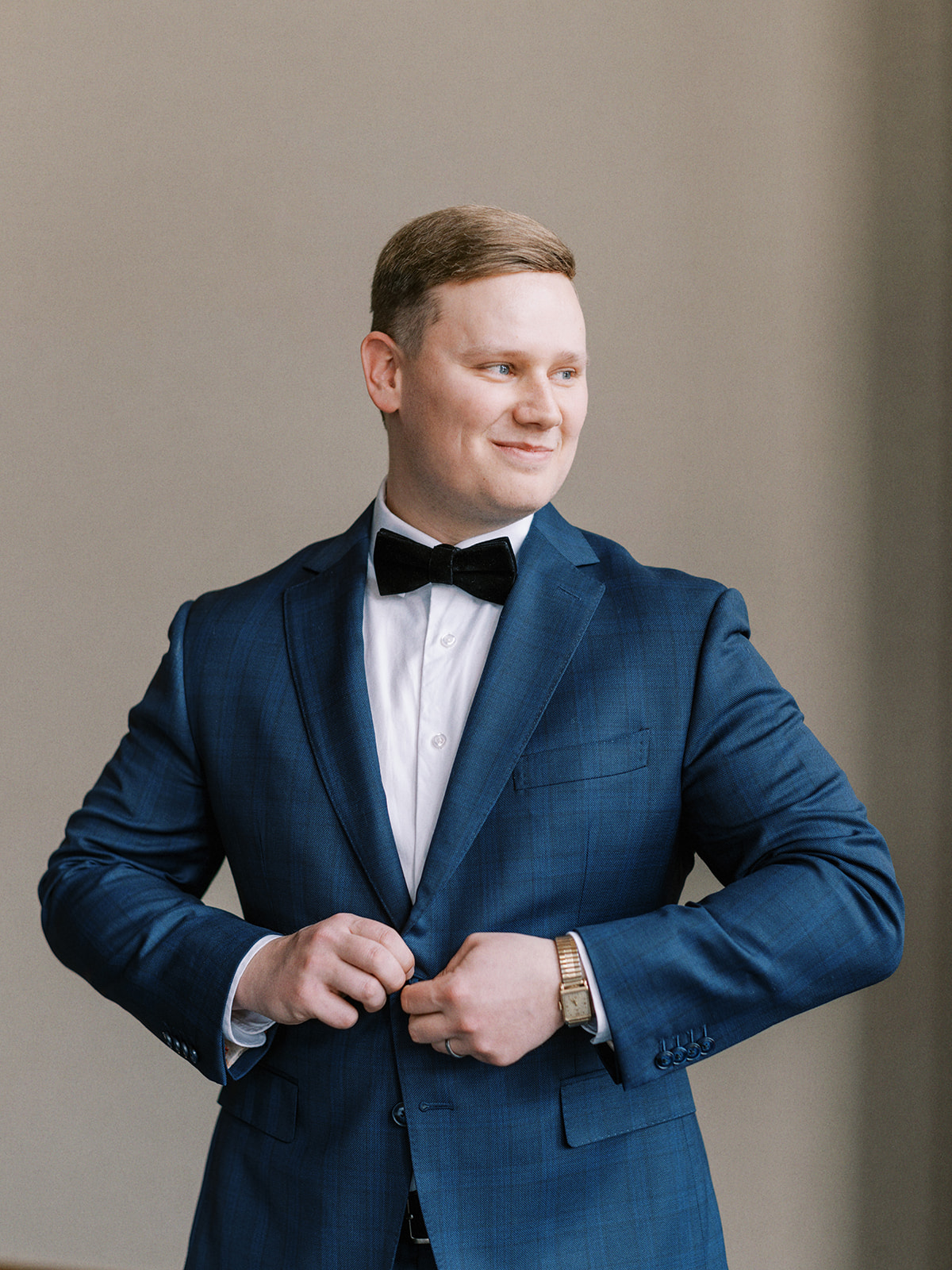 Sophisticated groom getting ready in classic blue plaid suit at The Malcom Hotel in Canmore, Alberta. Groom wedding attire inspiration with a navy suit and black velvet bow tie.