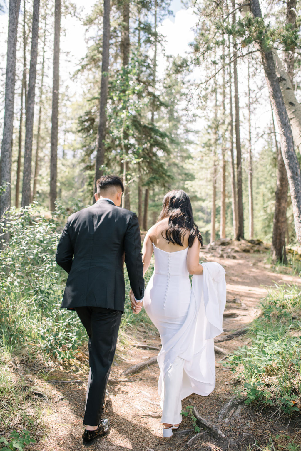 Elegant bride and groom walking in the mountains of Banff, Alberta. Canadian summer mountain wedding inspiration. Sophisticated mountain bridal portraits by Corrina Walker Photography. 