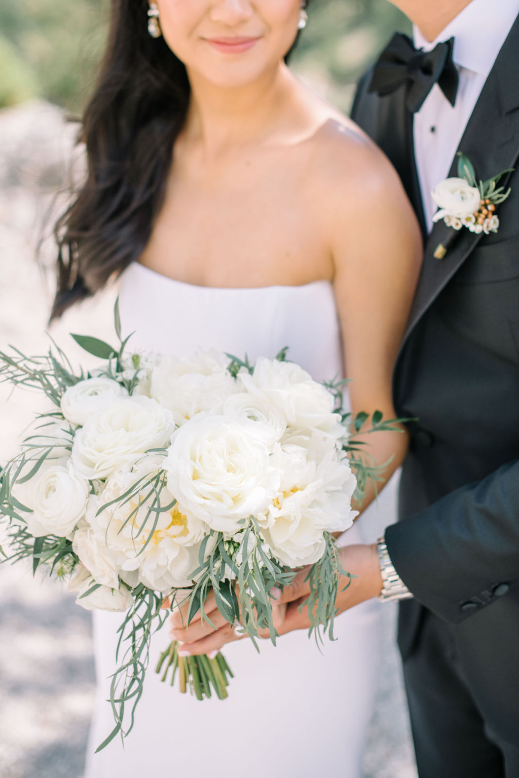 Bride wearing sleek form fitting white bridal gown, holding classic bouquet of white roses and greenery. Summer wedding inspiration in Banff, Alberta. 
