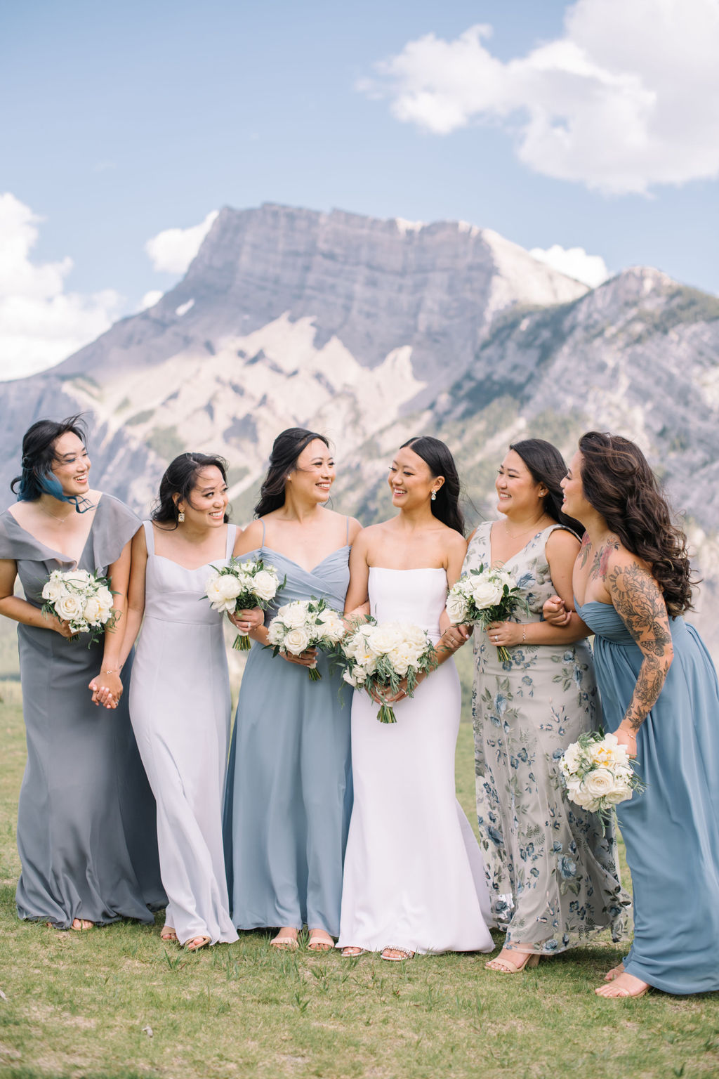 Bride with her bridesmaids in the mountains of Banff, Alberta, Canada. Elegant summer wedding inspiration, Classic neutral, blush, cremes, dusty blue colour scheme, white rose bouquets.