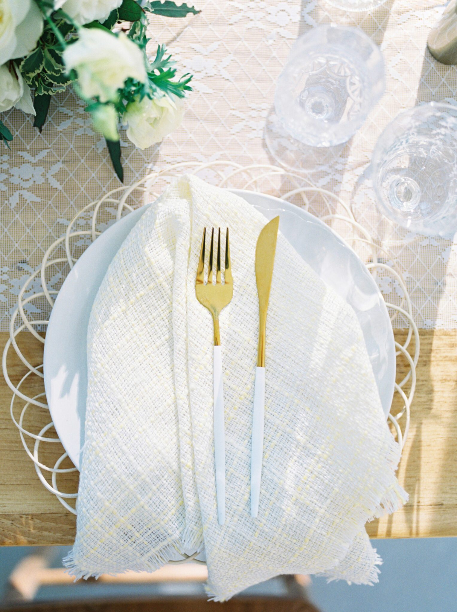 Elegant cottage core inspired wedding reception at Sparrow Lane Weddings and Events venue near Edmonton, Alberta. Fine art summer wedding. Outdoor summer wedding tablescape with lush florals in pale yellow, ivory and white with greenery. Wicker charger plates, and golden cutlery.
