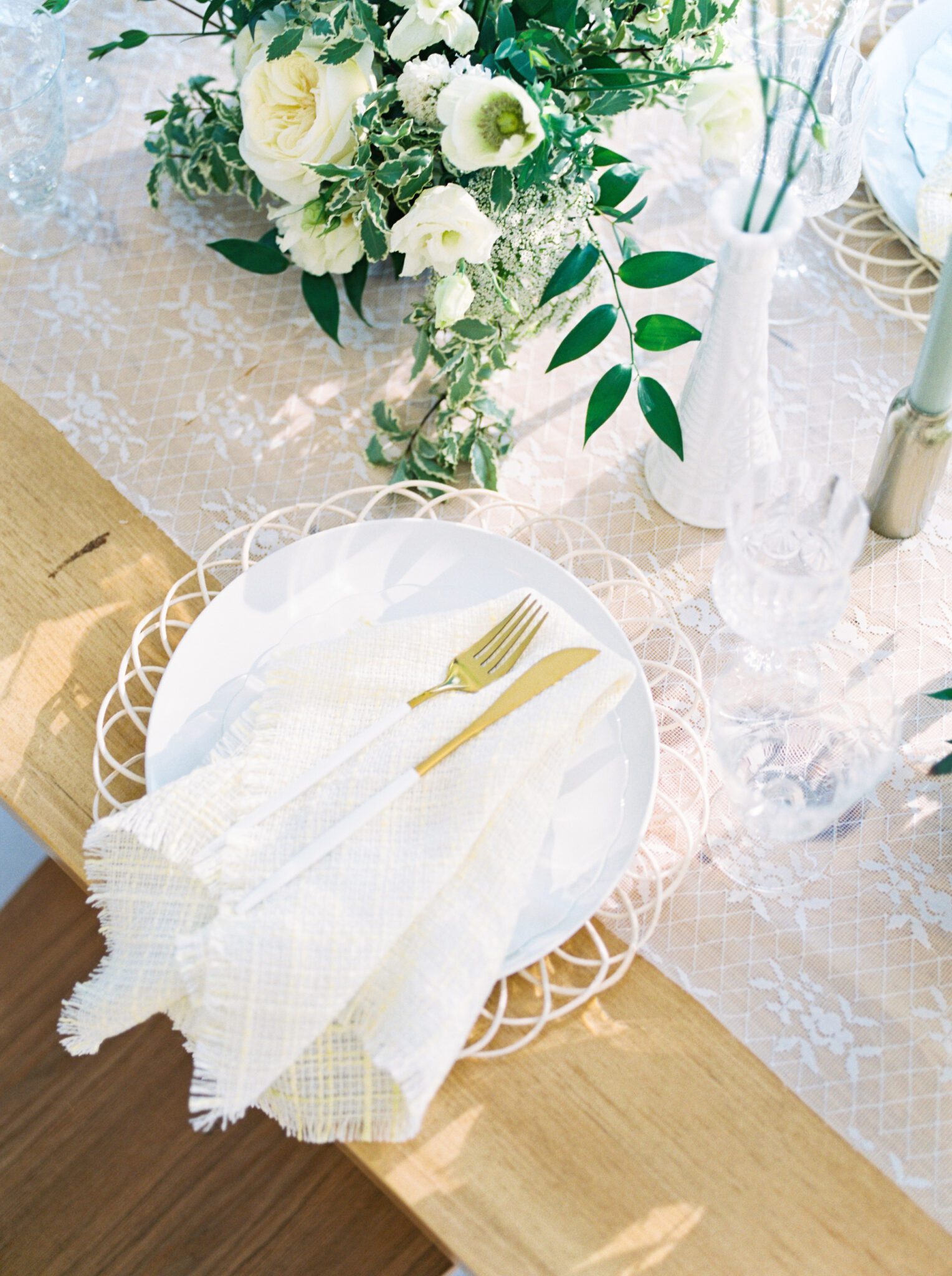 Elegant cottage core inspired wedding reception at Sparrow Lane Weddings and Events venue near Edmonton, Alberta. Fine art summer wedding. Outdoor summer wedding tablescape with lush florals in pale yellow, ivory and white with greenery. Wicker charger plates, and golden cutlery.