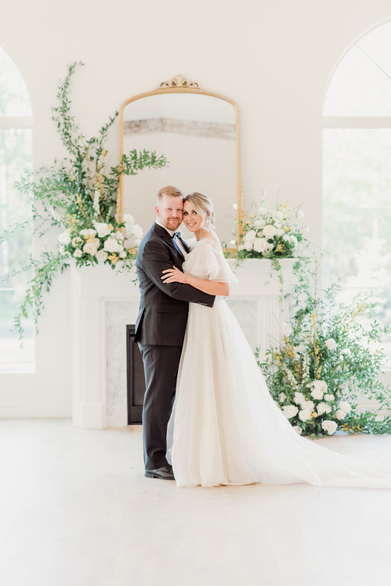 Bride and groom during fine art Indoor wedding ceremony at Sparrow Lane with a lush floral installation climbing up the fireplace. Pale yellow, ivory, white, colour palette. Bride wearing a whimsical yet sophisticated bridal gown.