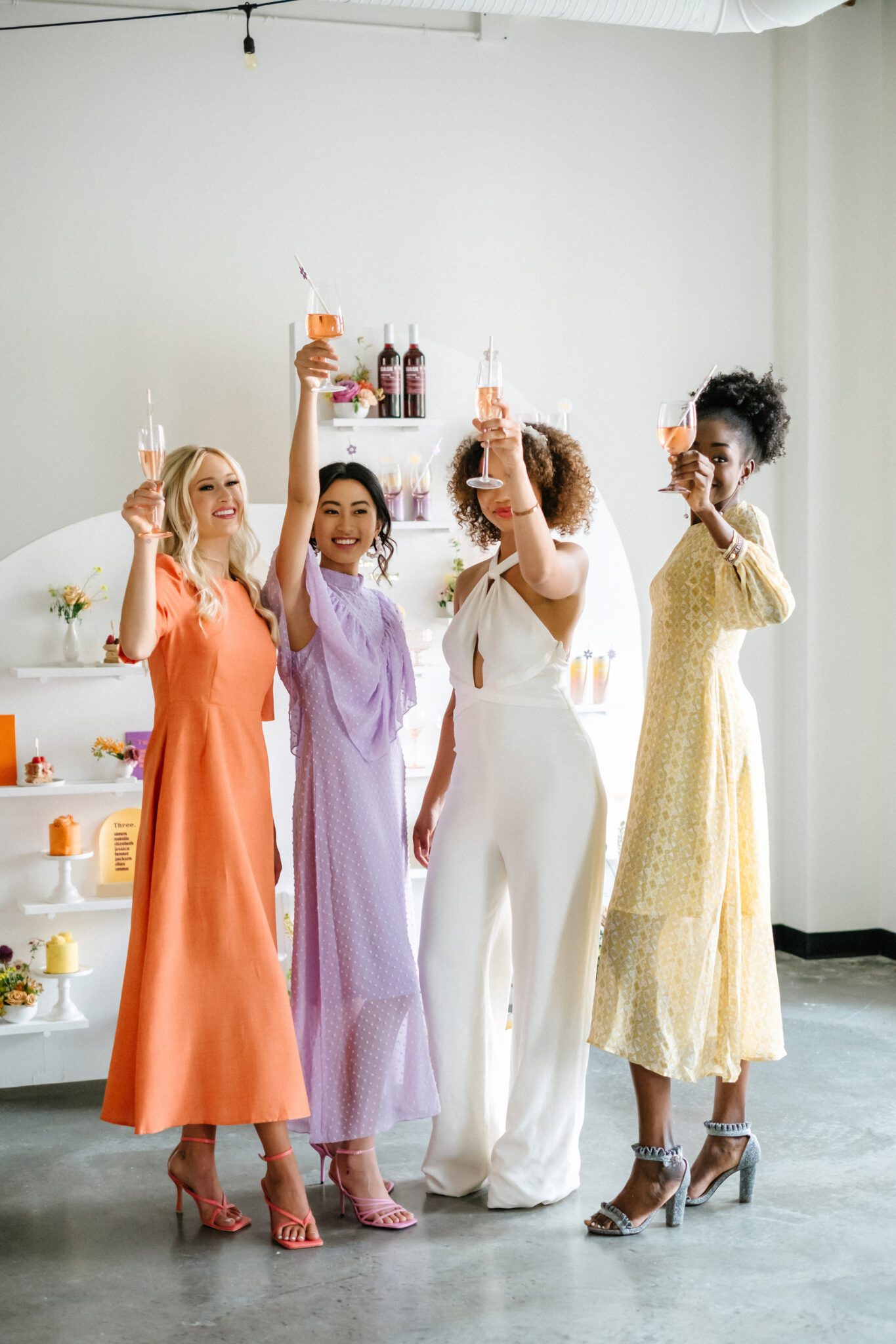Bright & Colourful Brunch Wedding Inspiration at The Brownstone Calgary, Bronte Bride. Retro-inspired vibrant colour palette of purple, orange, yellow, peach, tangerine and coral. Geometric hanging installation over the tables. Retro-inspired bridal jumpsuit and colourful bridesmaid dresses. 
