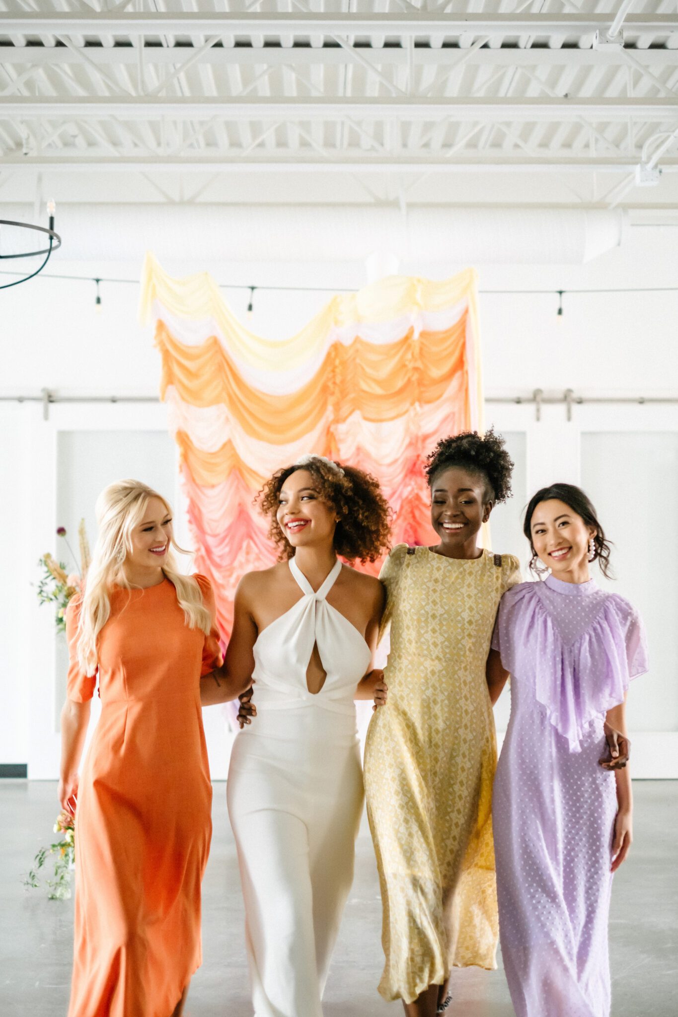 Bright & Colourful Brunch Wedding Inspiration at The Brownstone Calgary, Bronte Bride. Retro-inspired vibrant colour palette of purple, orange, yellow, peach, tangerine and coral. Geometric hanging installation over the tables. Retro-inspired bridal jumpsuit and colourful bridesmaid dresses. 
