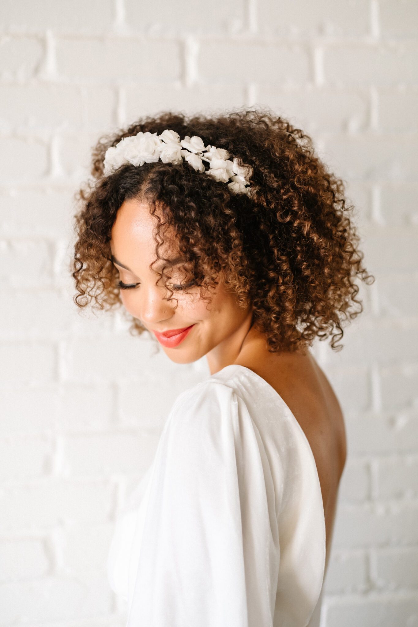 Bride wearing short bridal gown with long draped sleeves and low back, white floral headband by Simone Martin.