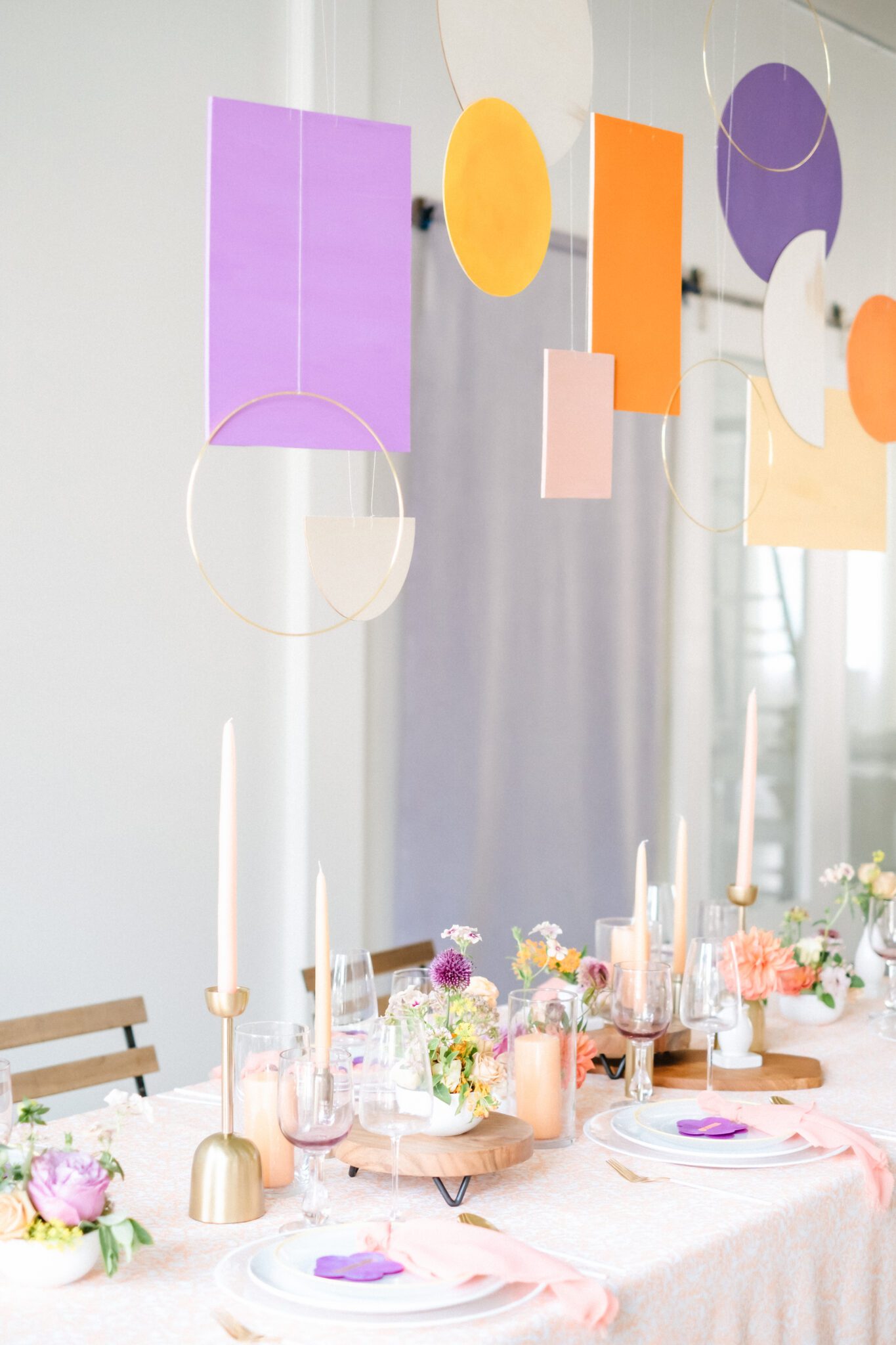 Bright & Colourful Brunch Wedding Inspiration at The Brownstone Calgary, Bronte Bride. Retro inspired vibrant colour palette of purple, orange, yellow, peach, tangerine and coral. Geometric hanging installation over the tables. 