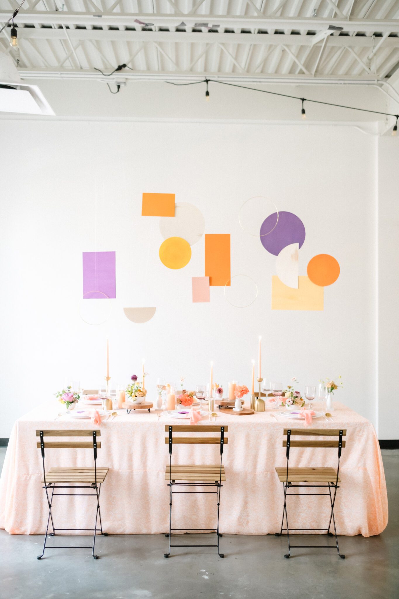 Bright & Colourful Brunch Wedding Inspiration at The Brownstone Calgary, Bronte Bride. Retro inspired vibrant colour palette of purple, orange, yellow, peach, tangerine and coral. Geometric hanging installation over the tables. 