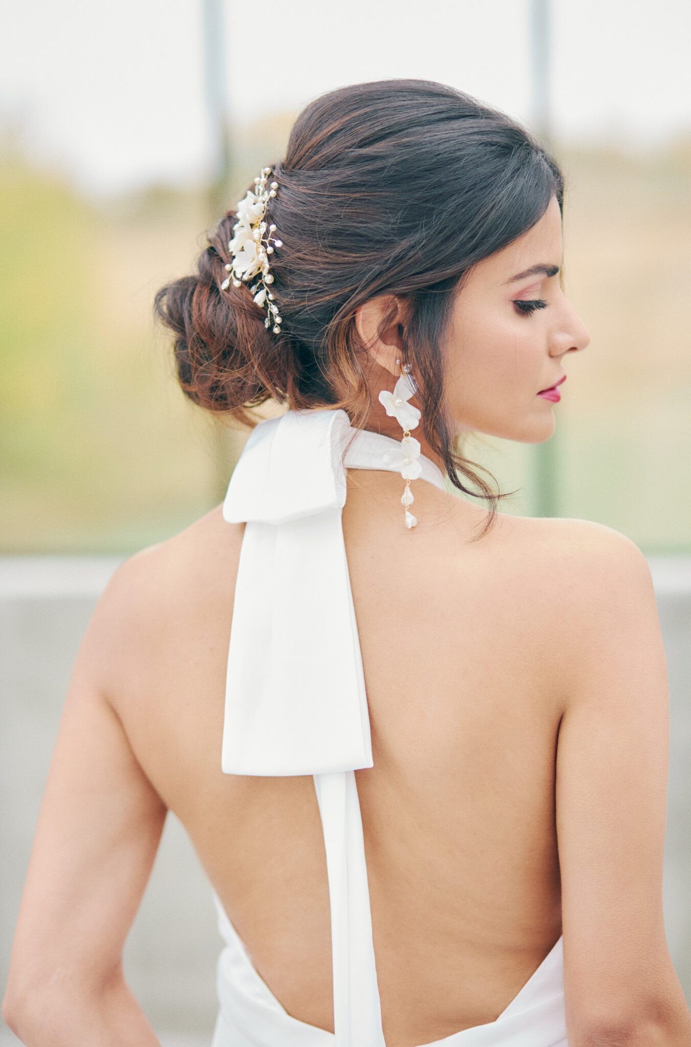 Elegant and modern bride wears a backless wedding dress, pearl hairpiece, and statement earrings by Joanna Bisley Designs.