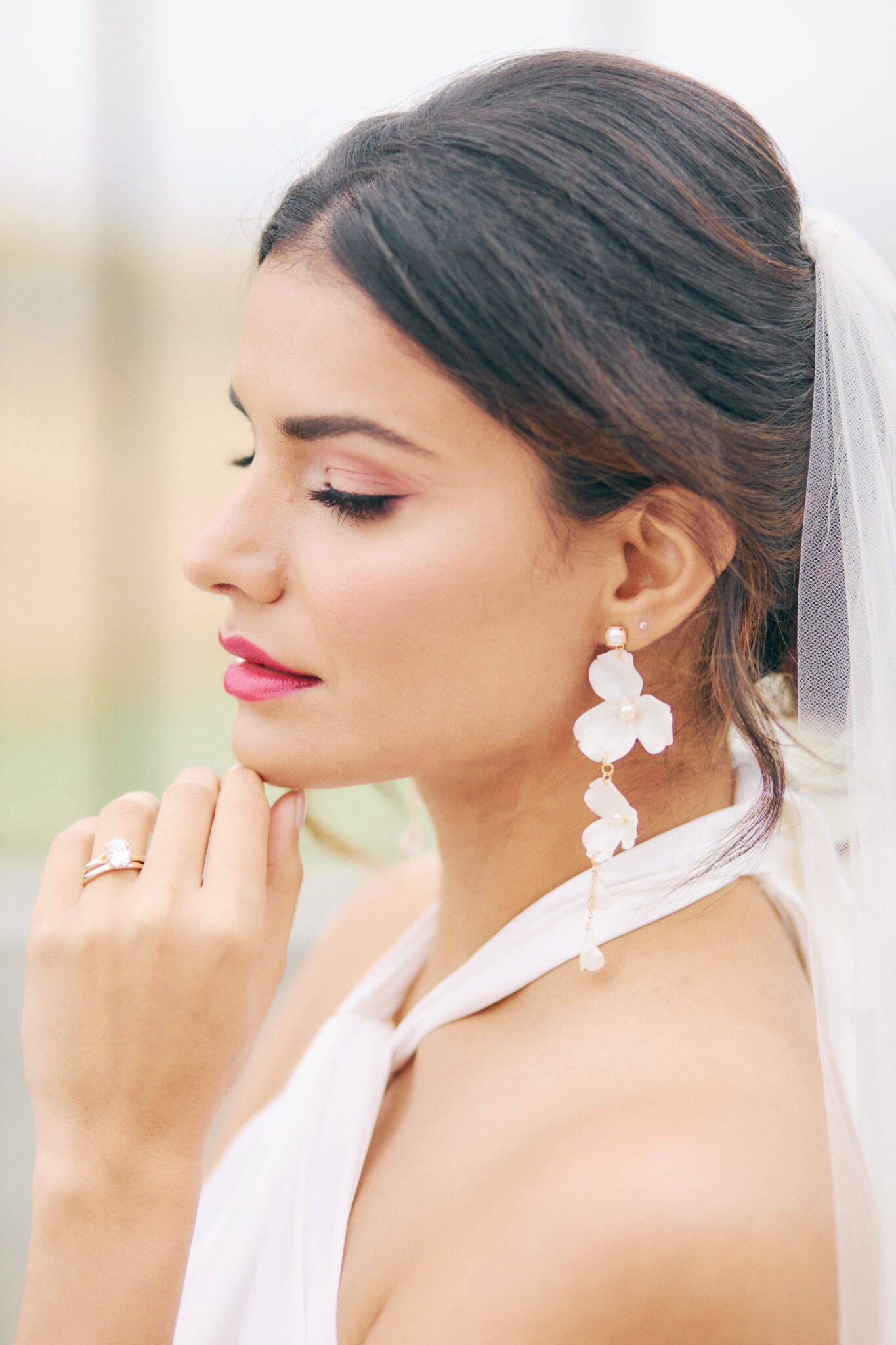 Elegant and modern bride wears a backless wedding dress, pearl hairpiece, and statement earrings by Joanna Bisley Designs.