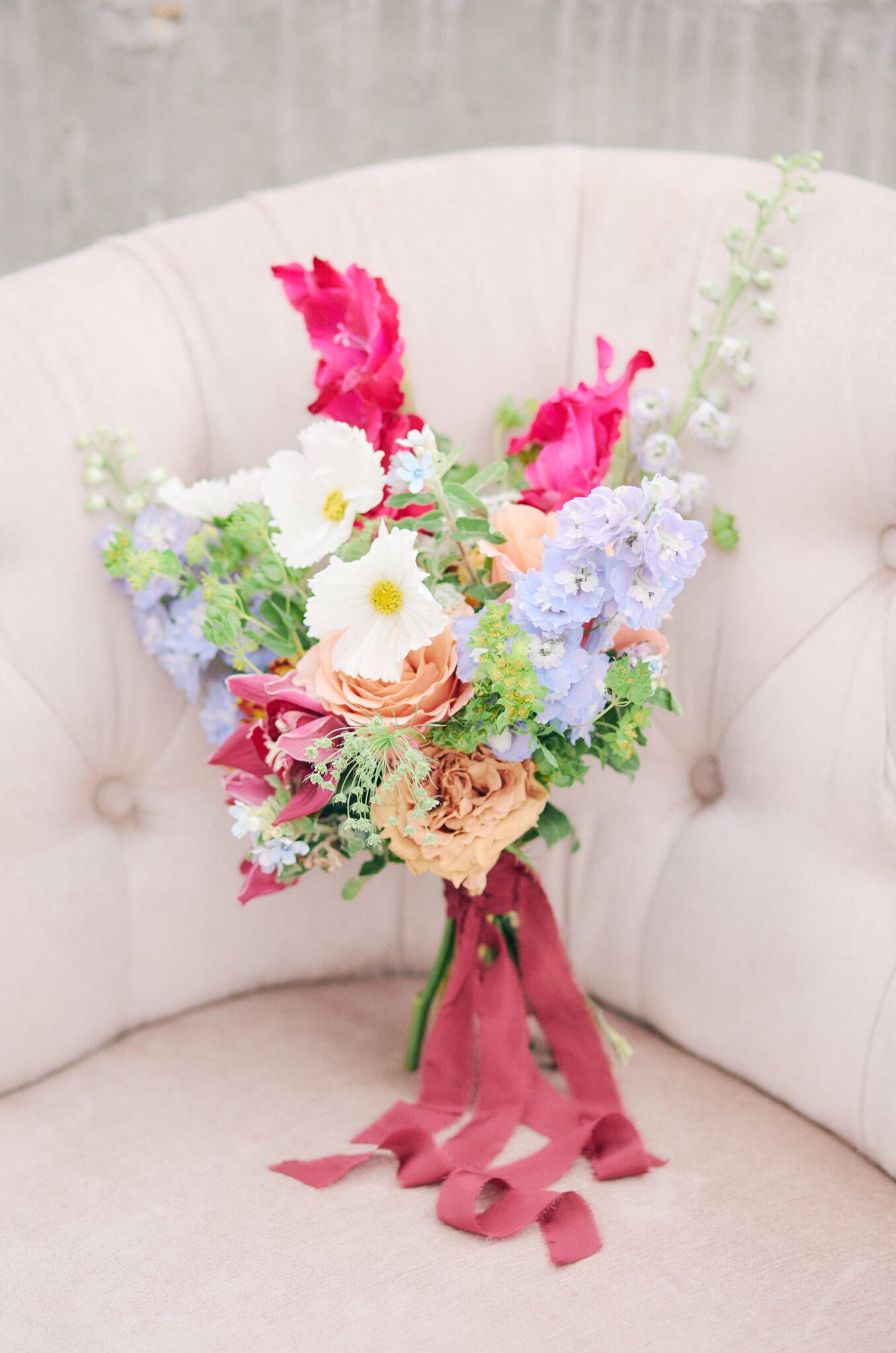 Bold and vibrant wedding bouquet of hot pink, violet, orange, peach and burgundy. 