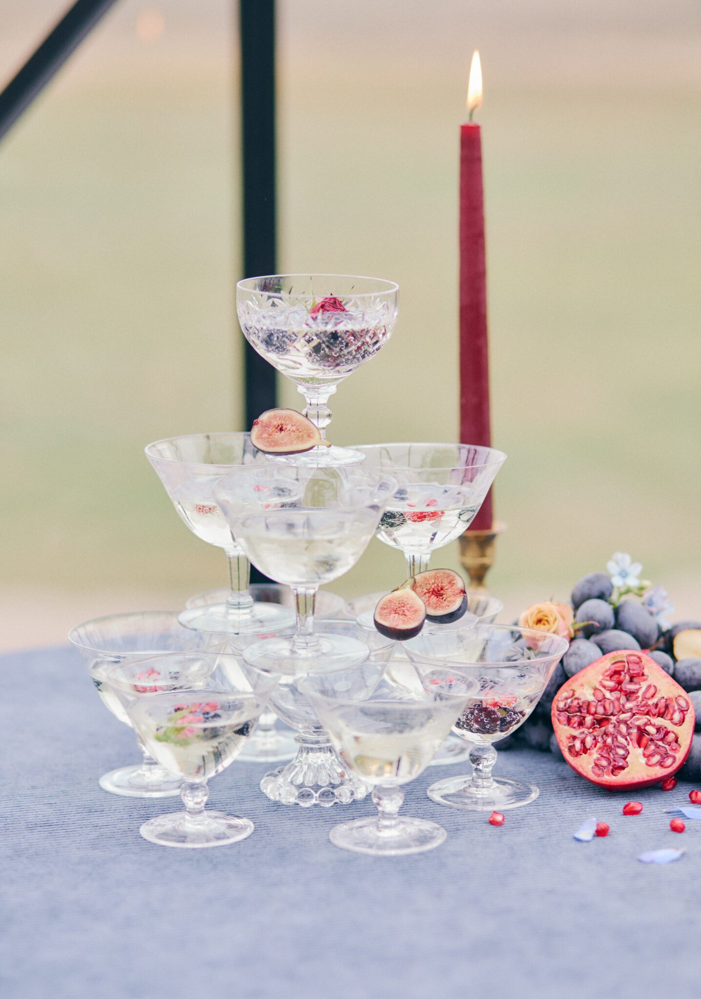 Elegant champagne tower with fruit details. Vibrant and bold wedding inspiration. Blur corduroy linens and burgundy candles with hints of gold detail. 